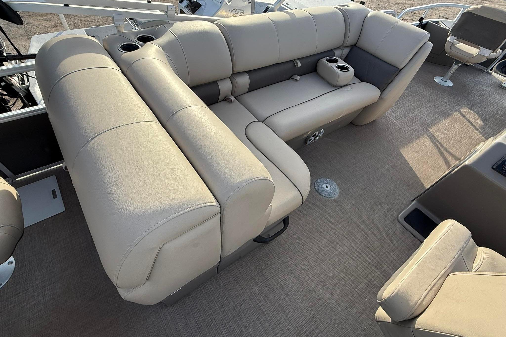 2023 Sun Tracker Fishin' Barge 22 DLX interior with beige seating and cup holders.