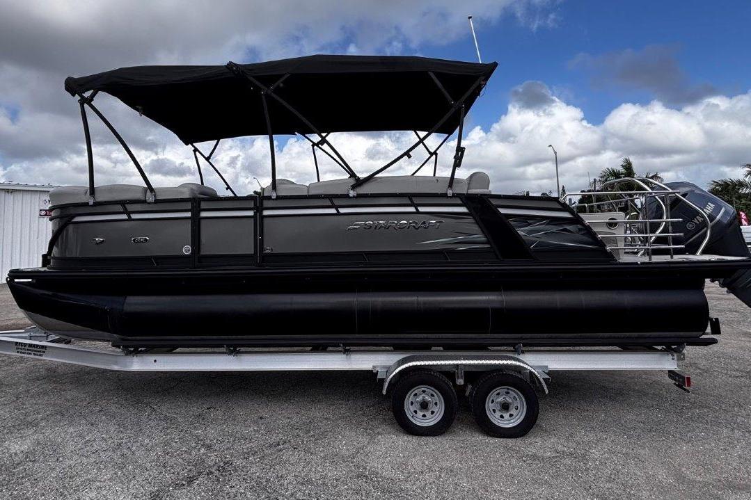 2023 Starcraft CX 23 DL BAR pontoon boat on trailer, black canopy, overcast sky.