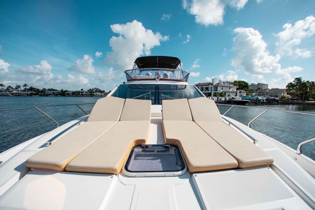 Luxurious 2015 Absolute 56 FLY yacht with sun loungers on deck, under a bright blue sky.