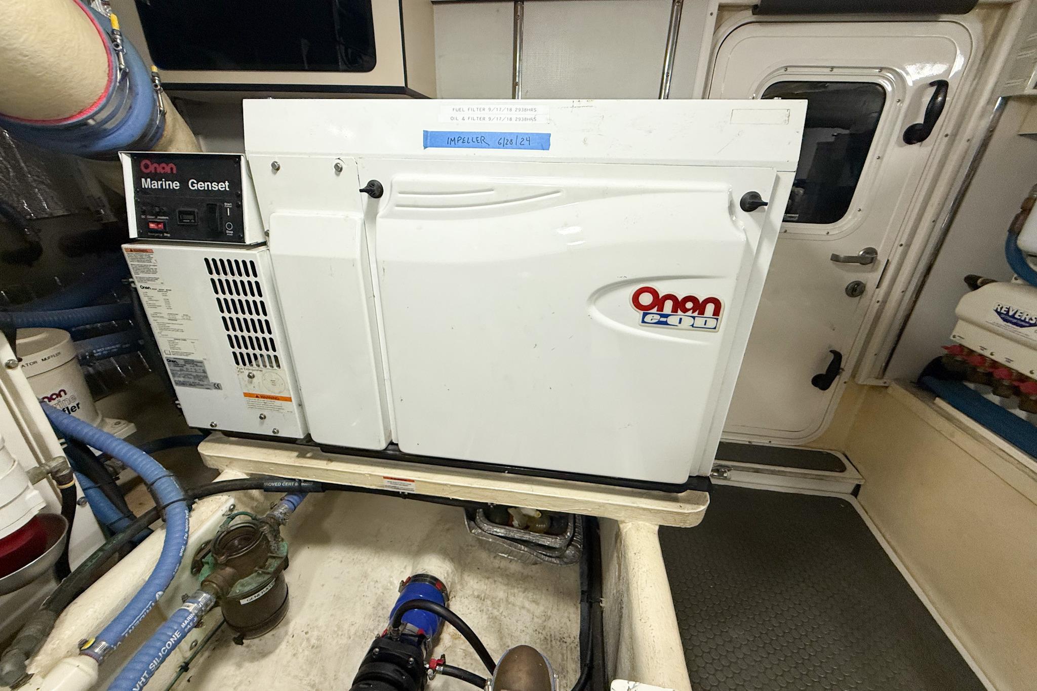 Onan Marine Genset in 2007 Nordic Tug 54 engine room, featuring white casing and blue hoses.