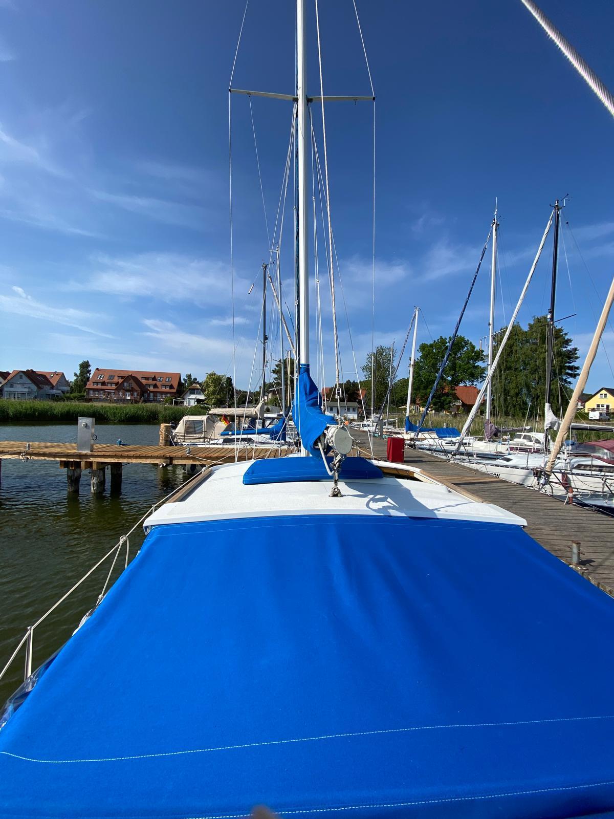 1980 LM 32 sailboat docked, featuring blue covers and clear sky background.