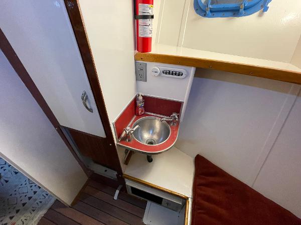 1951 Chris-Craft Catalina interior with compact sink, fire extinguisher, and wooden flooring.