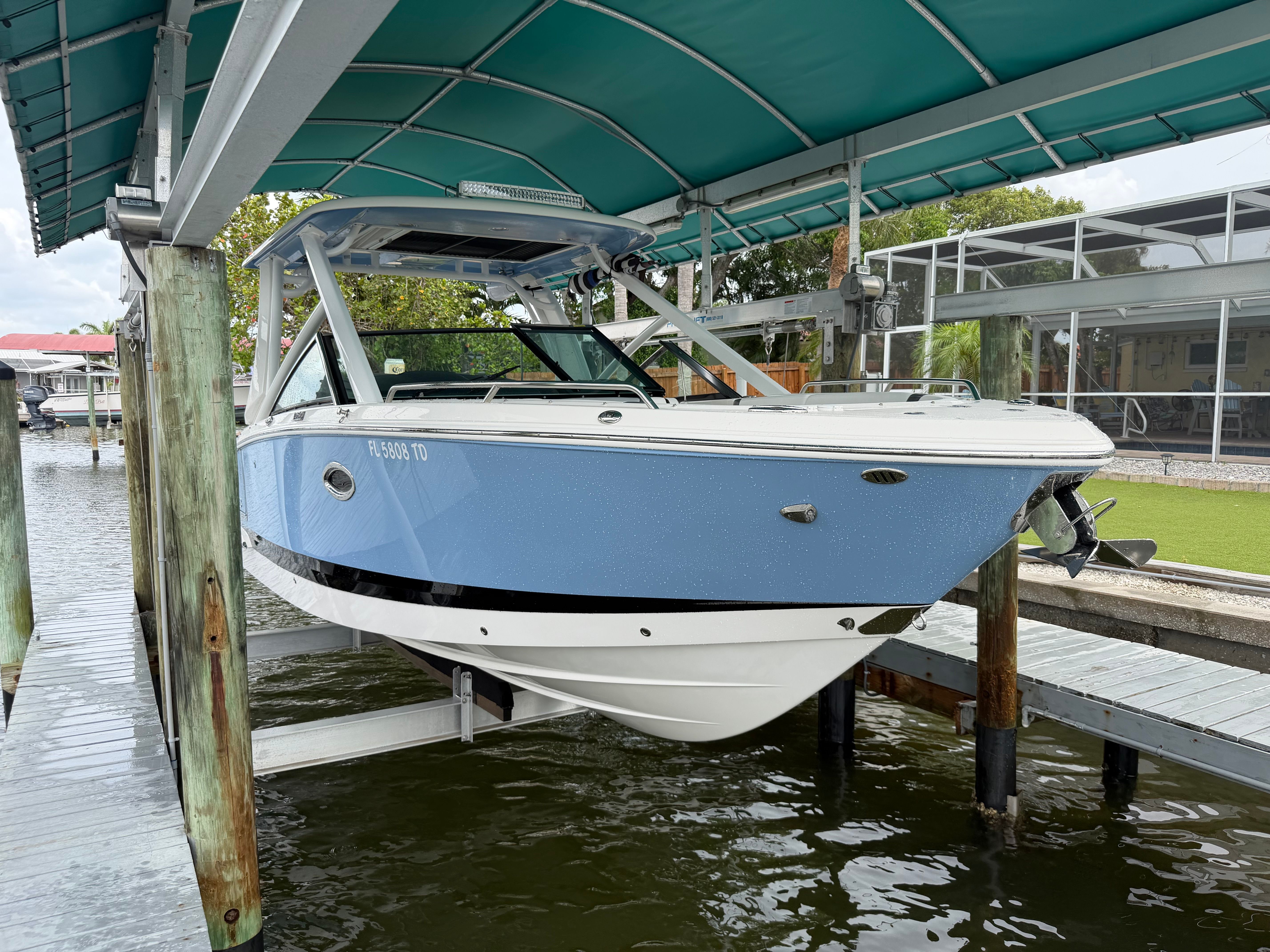 A blue and white Chaparral 280 OSX boat is lifted in a covered dock.