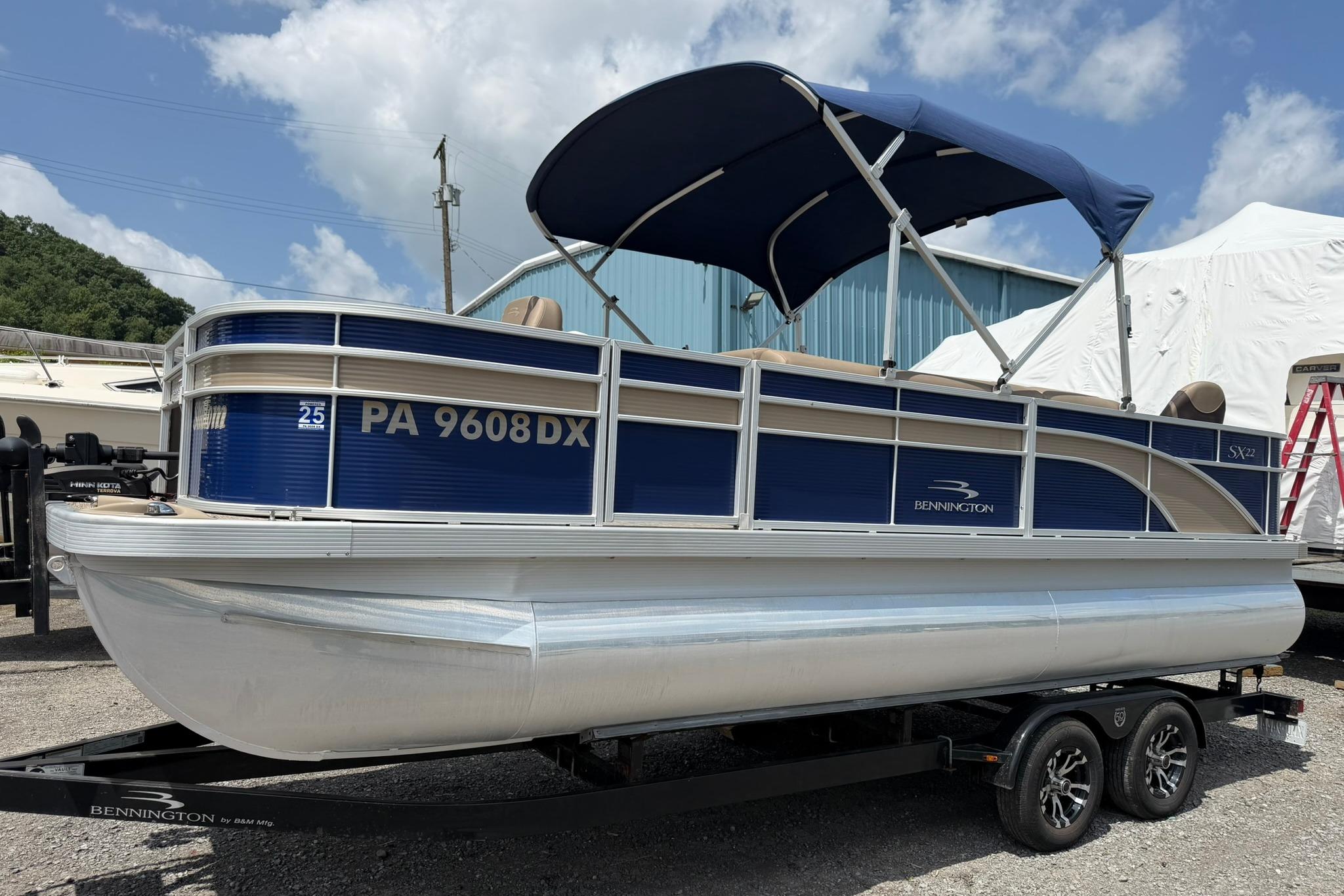 2020 Bennington SX 22 SFX pontoon boat with blue canopy on trailer.