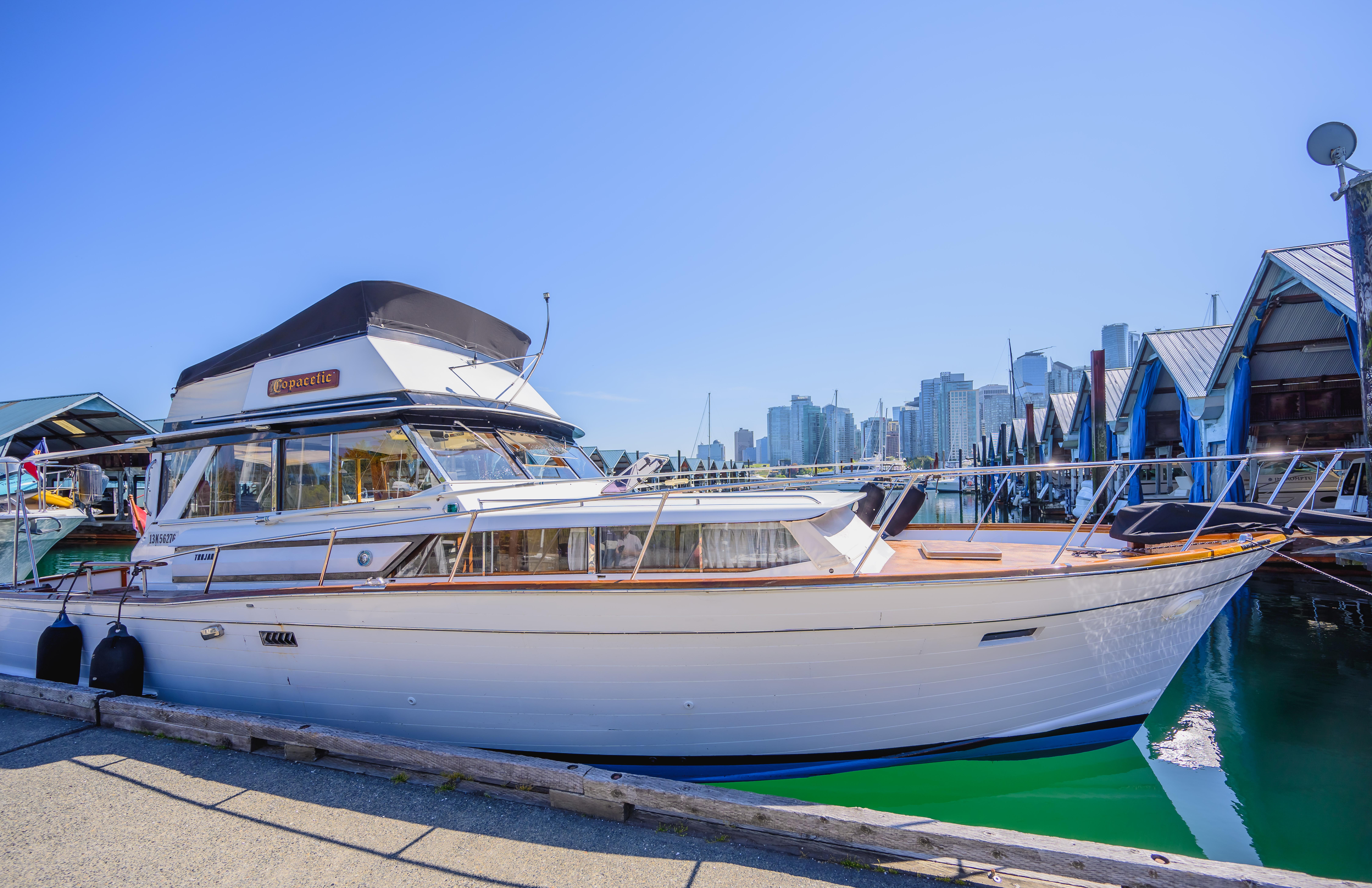 1968 Trojan 3700 Sea Voyager docked at marina with city skyline in background.