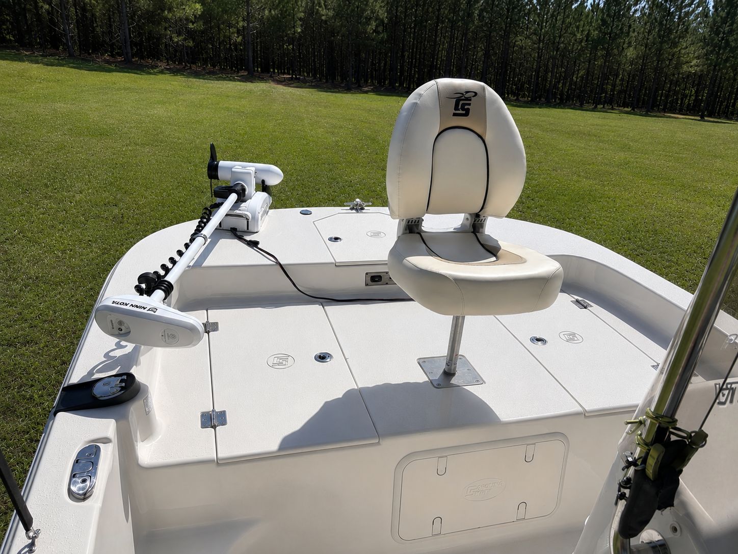A 2022 Carolina Skiff 17 LS with an elevated seat and motor on a grassy area.