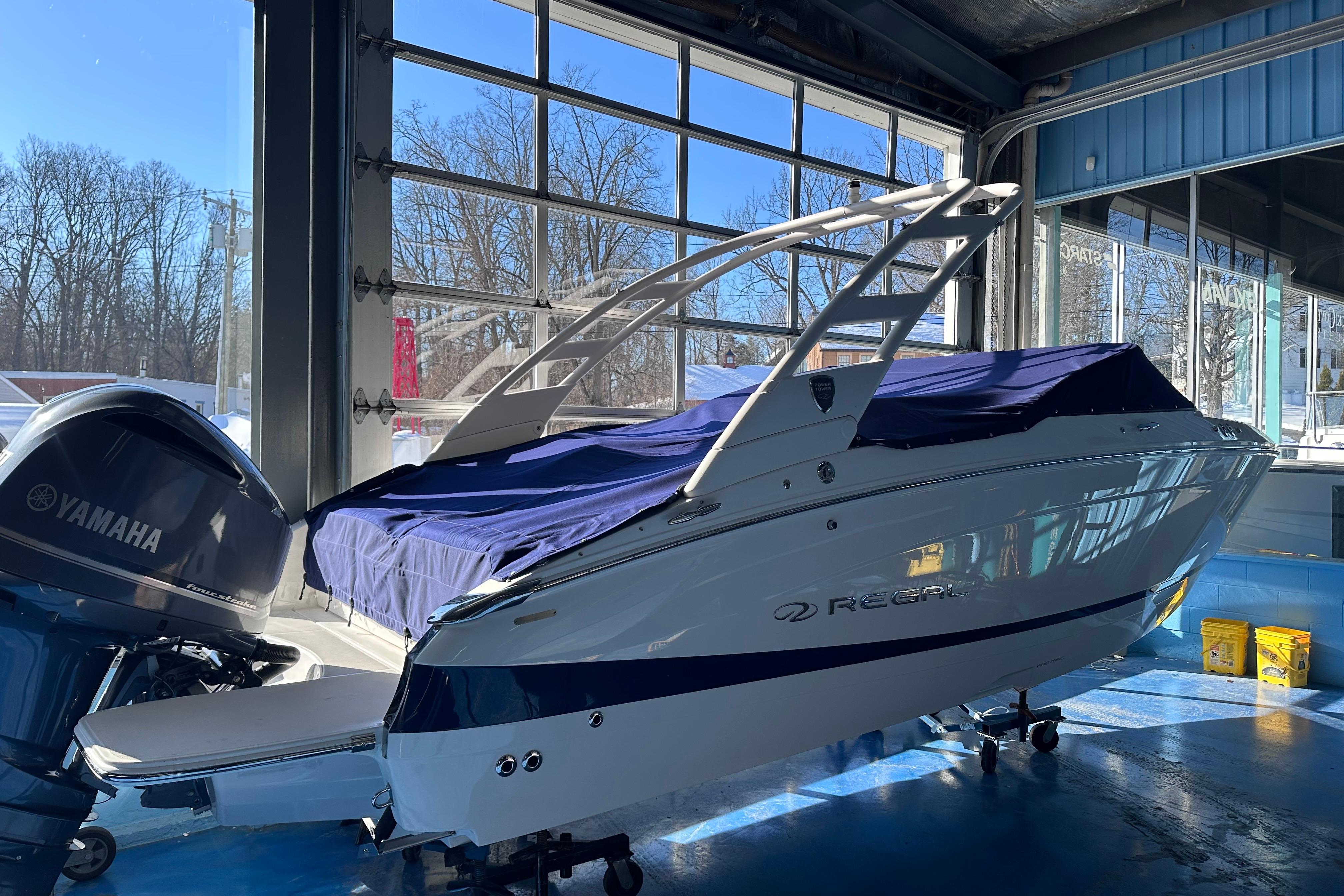 2026 Regal LX4 boat in showroom, covered with blue tarp, Yamaha engine visible.
