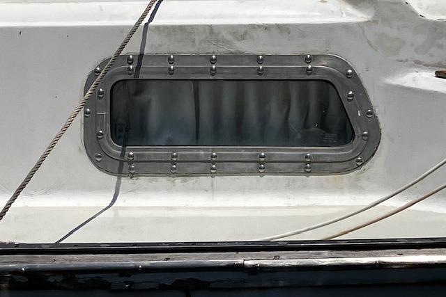 1979 Pearson 365 Ketch boat window with metal frame and curtain.