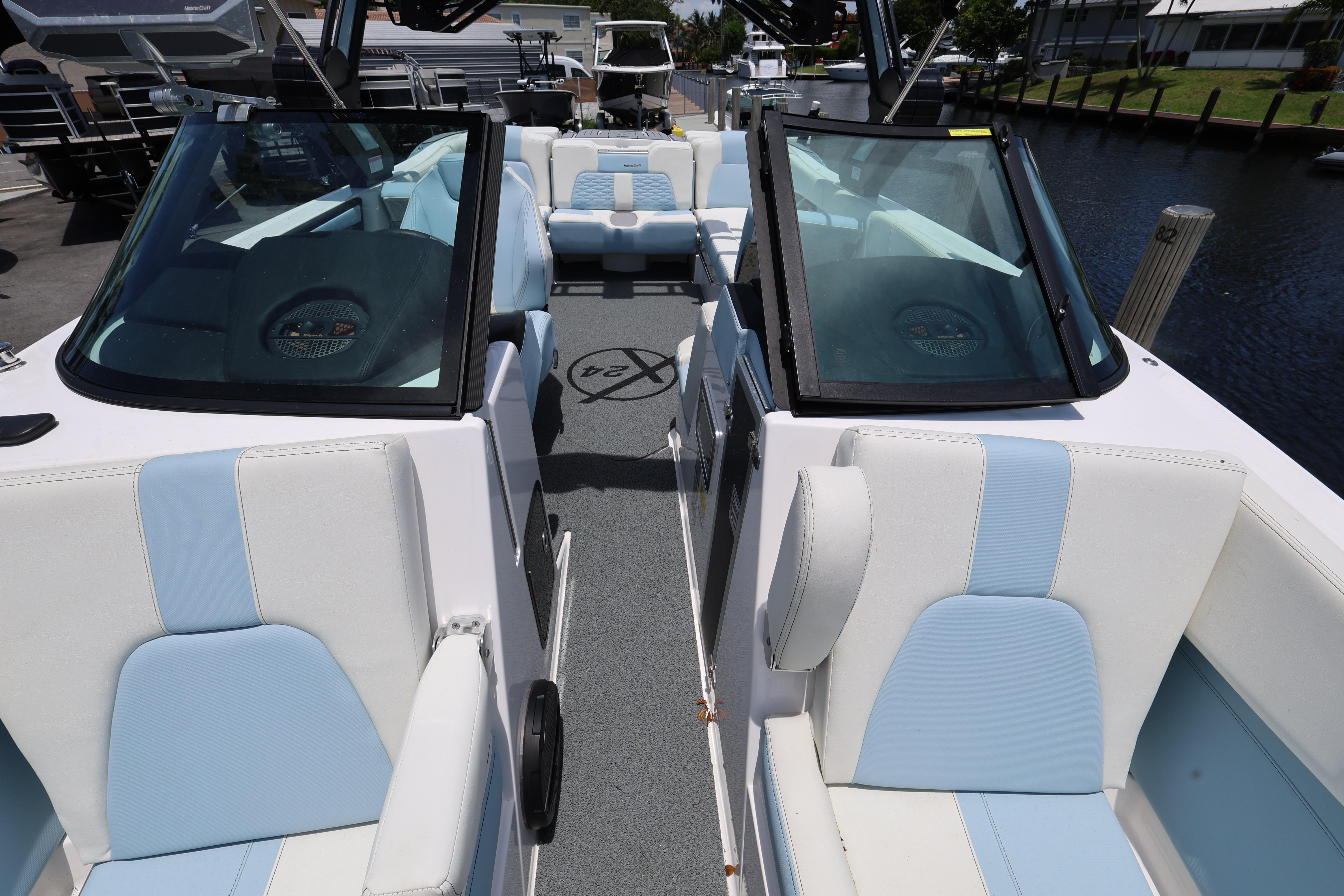 2023 MasterCraft X24 boat interior with blue and white seating, docked by a canal.