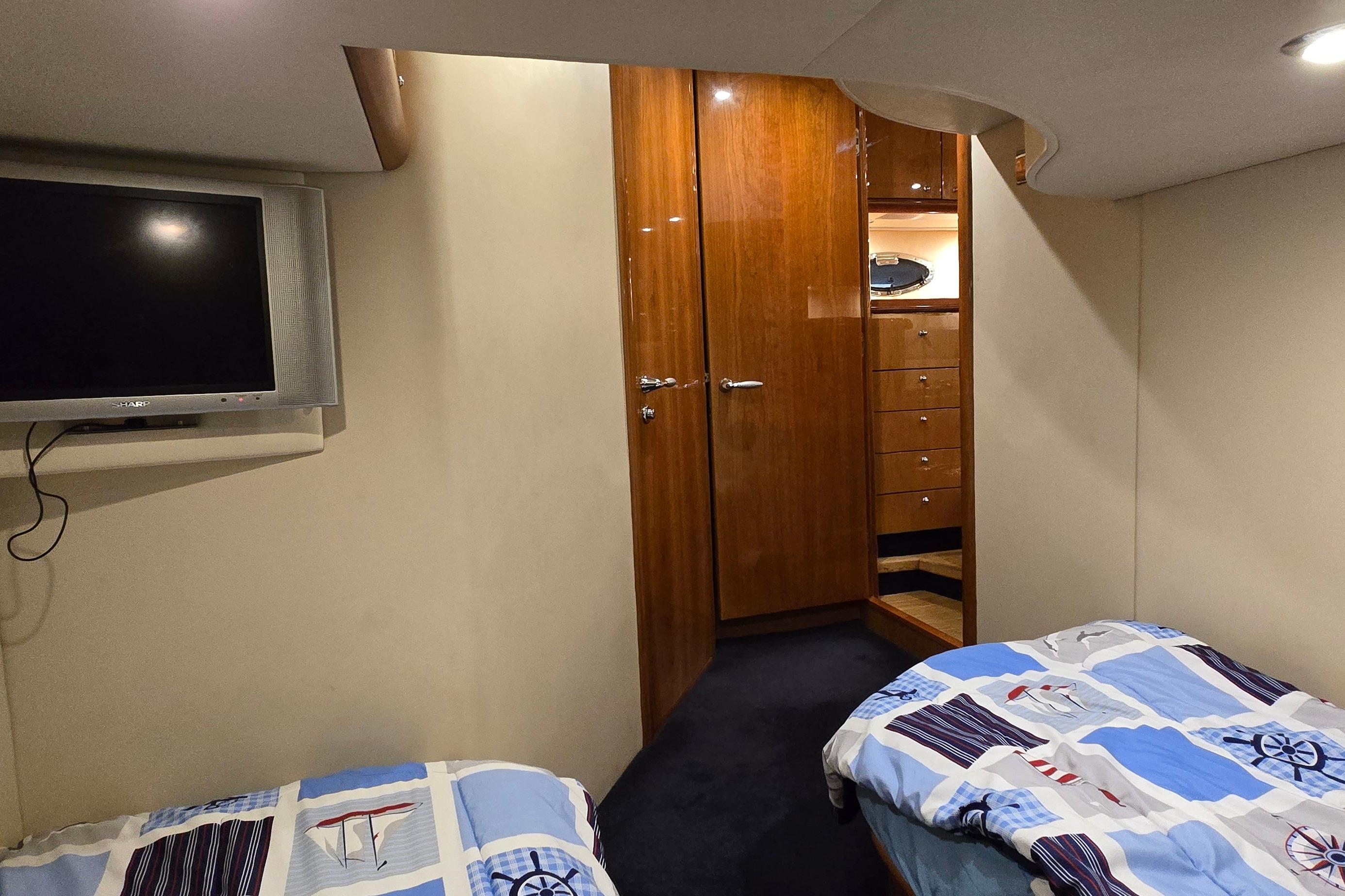 Interior cabin of 2004 Sunseeker Camargue 50 yacht with twin beds and TV.