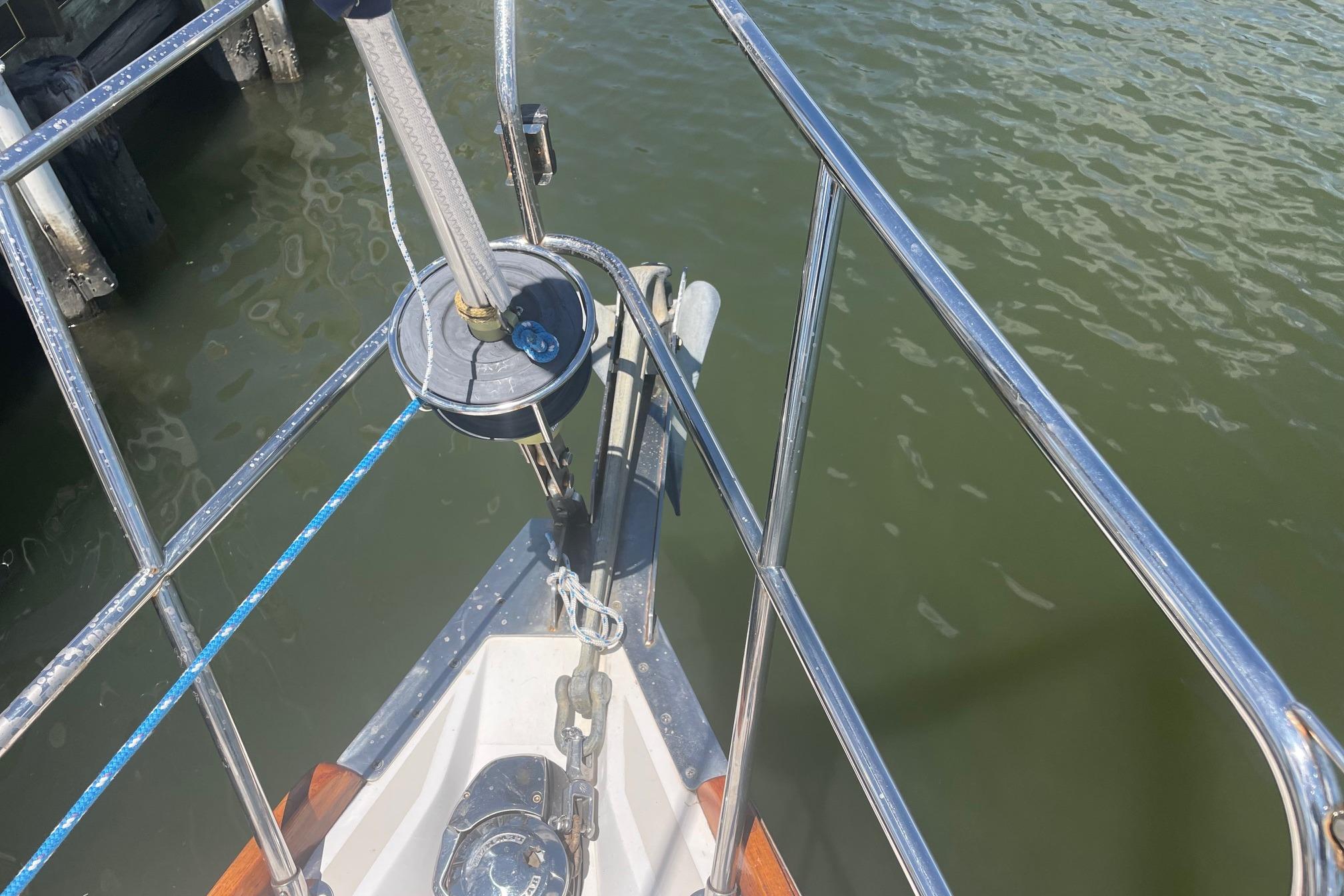 Bow of 2001 Tartan 3700 sailboat with stainless steel railing and anchor, docked on calm water.
