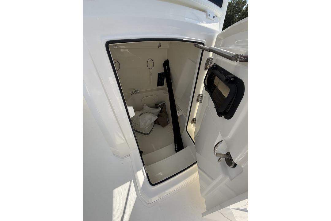 Interior cabin view of 2026 Pathfinder 2800 Hybrid boat, featuring open door and storage space.