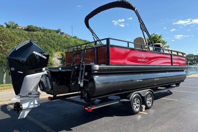 2025 Regency 250 DL3 pontoon boat with Mercury engine on trailer, parked outdoors.