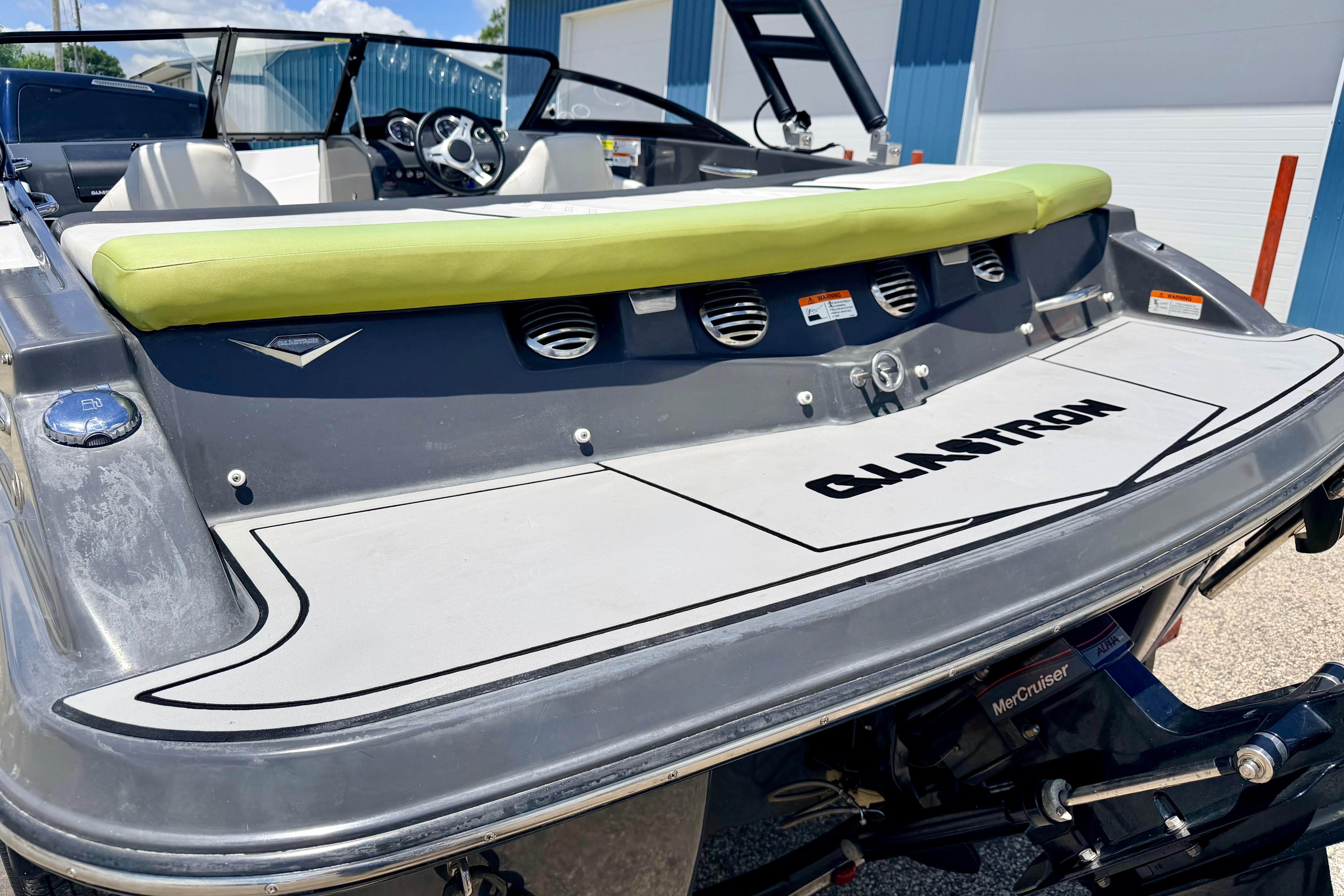 2018 Glastron GT 185 boat with green cushion and MerCruiser engine, docked outdoors.