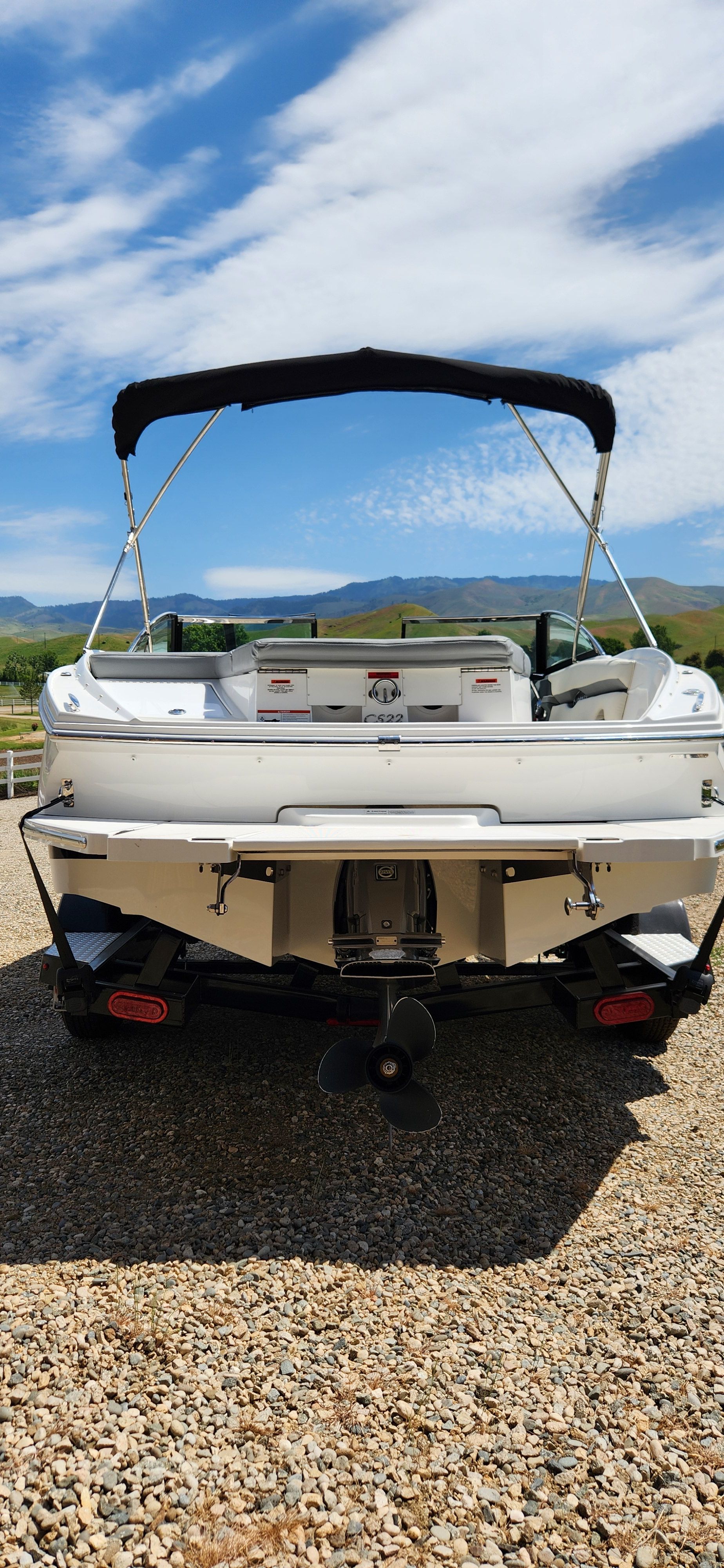 A Cobalt CS22 boat is on a gravel lot with mountains in the background.