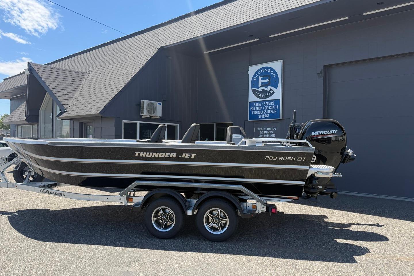 2026 Thunder Jet 209 Rush OT boat on trailer outside marine service building.