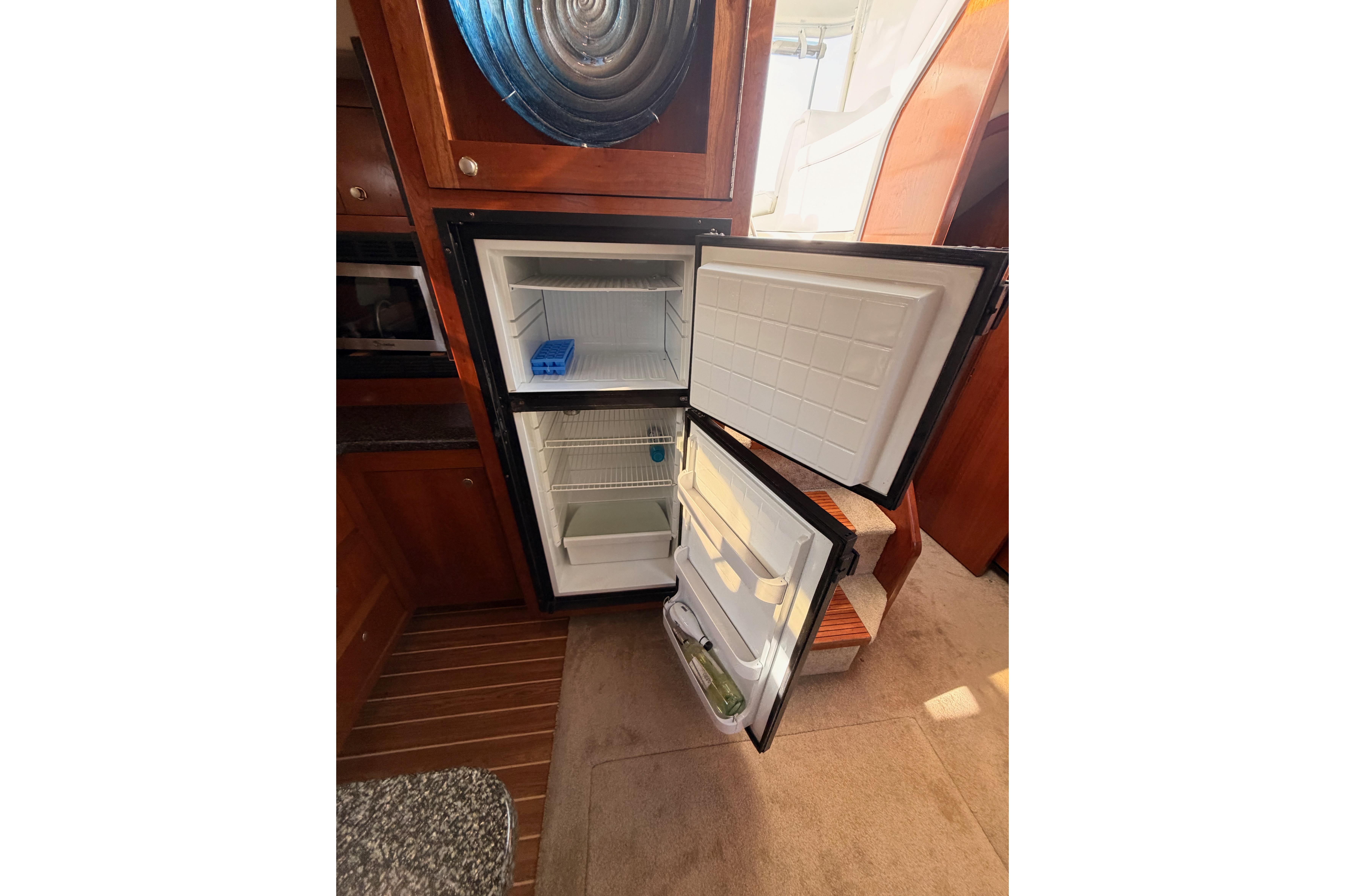 Open refrigerator inside 2005 Cruisers Yachts 405 Express Motoryacht, showcasing interior storage.