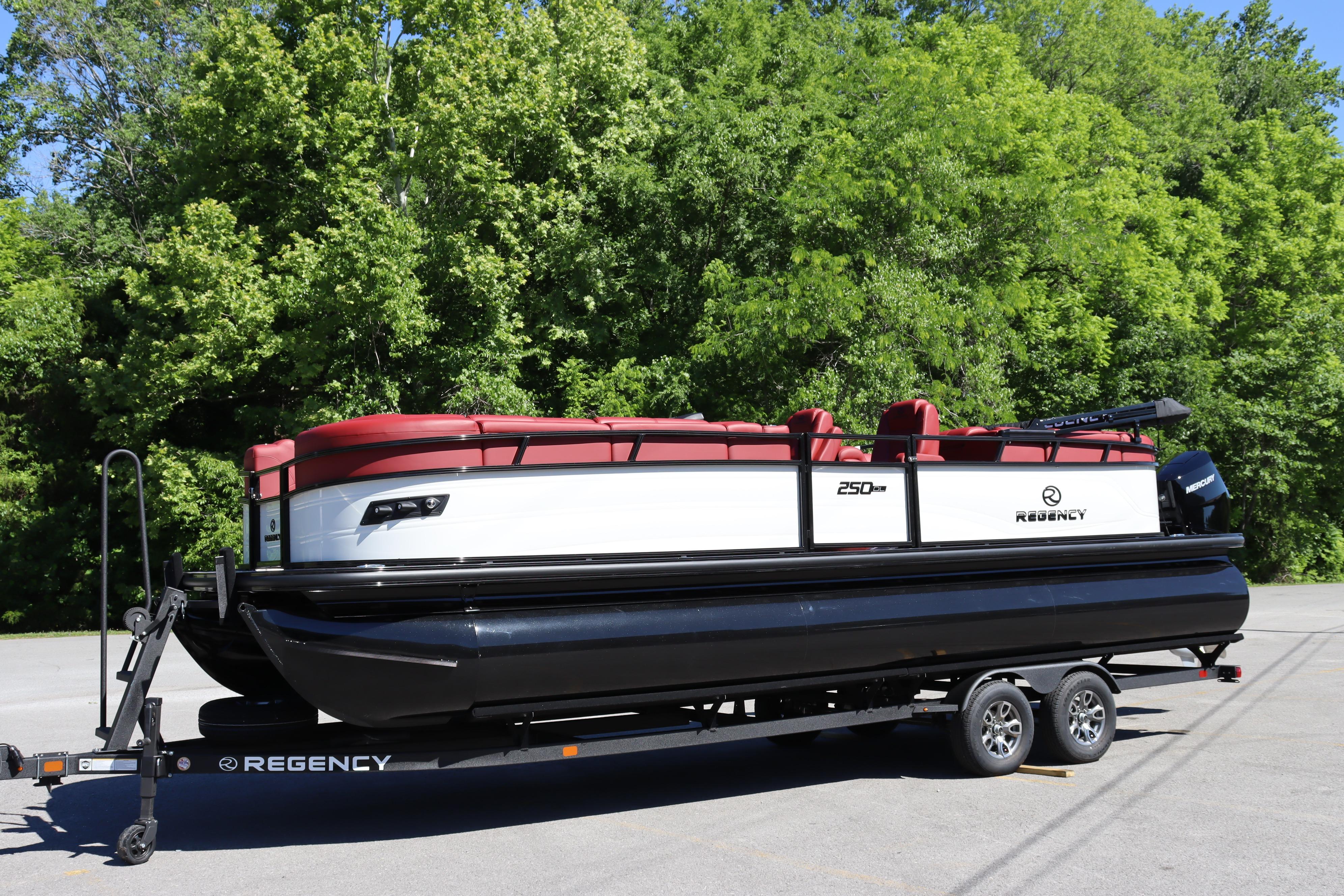 2026 Regency 250 DL pontoon boat on trailer, surrounded by lush green trees.