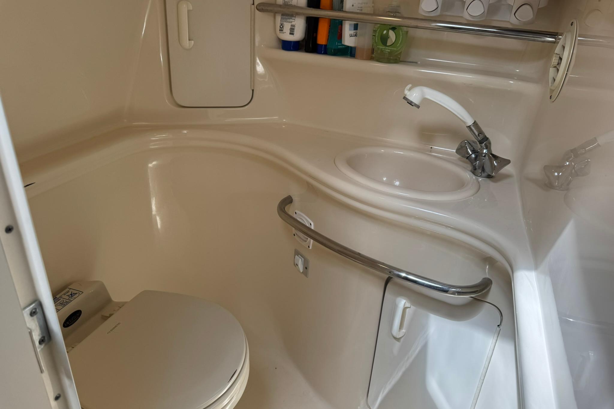 2001 Sea Ray 340 Sundancer bathroom with sink, toilet, and storage shelves.