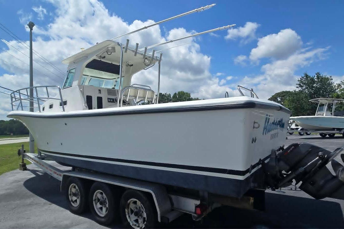 2003 True World Marine 286 boat on trailer under a partly cloudy sky.