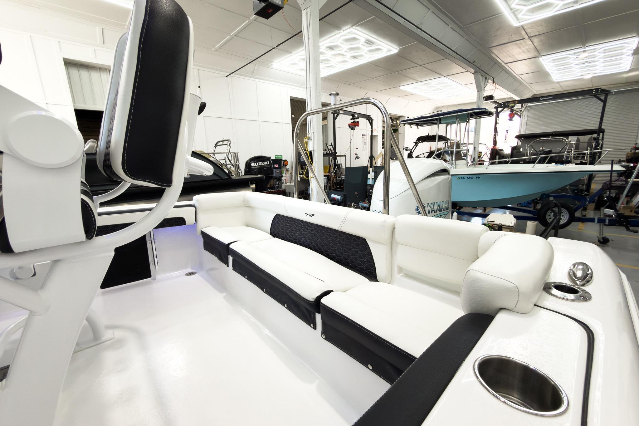 Interior view of a modern boat with white and black seating in a workshop.
