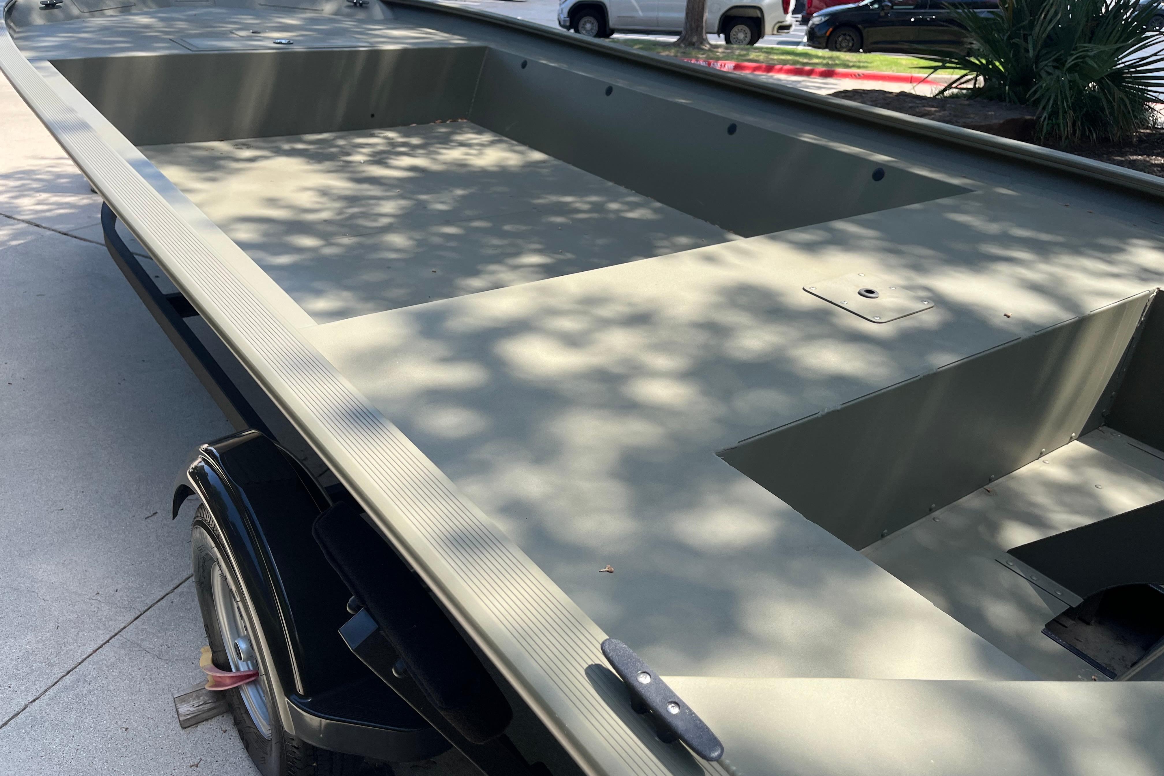 2025 Tracker GRIZZLY 1860 Utility boat, olive green, parked on concrete driveway.