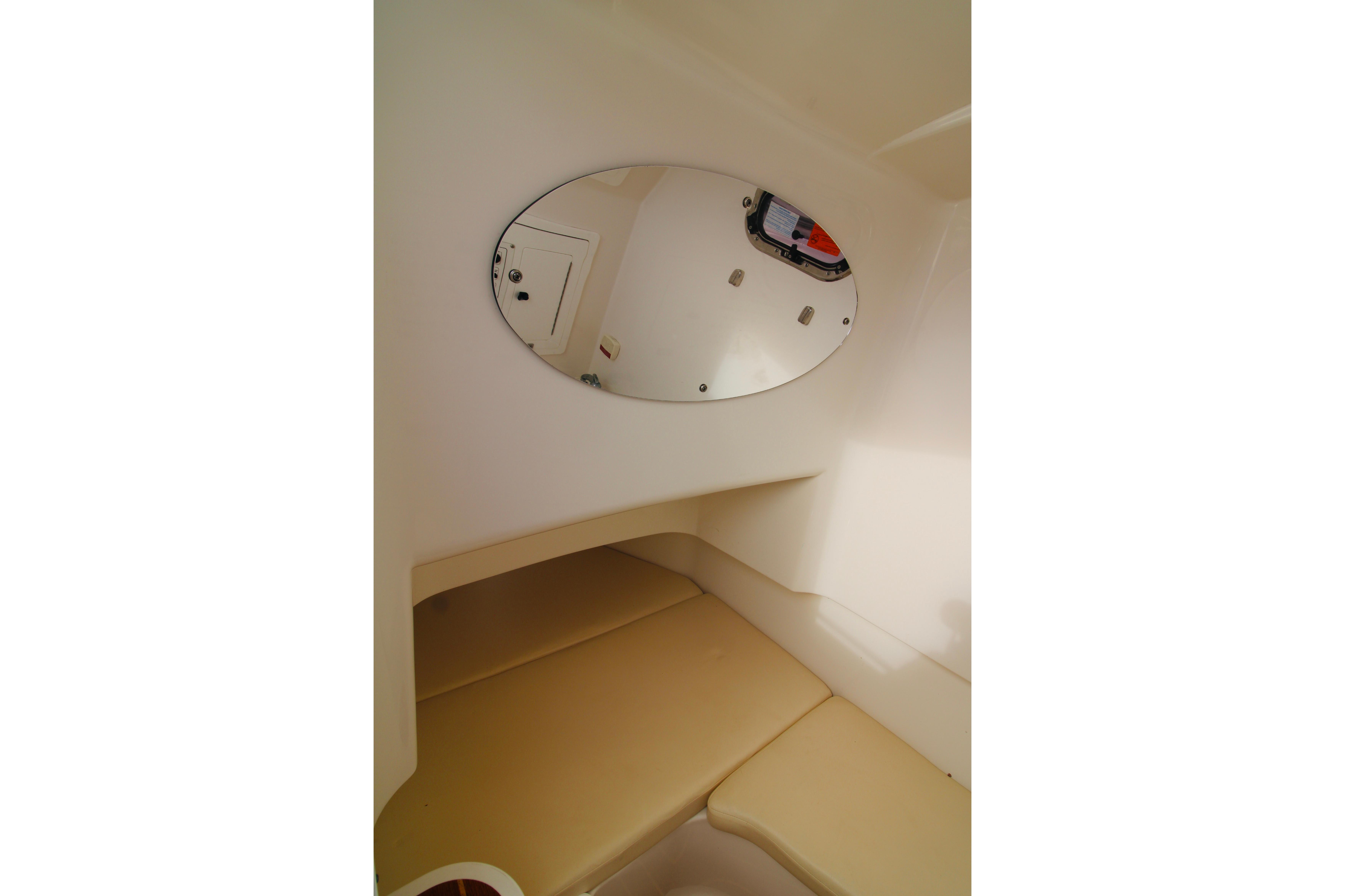 Interior cabin of 2022 Edgewater 280CC boat with beige seating and oval mirror.