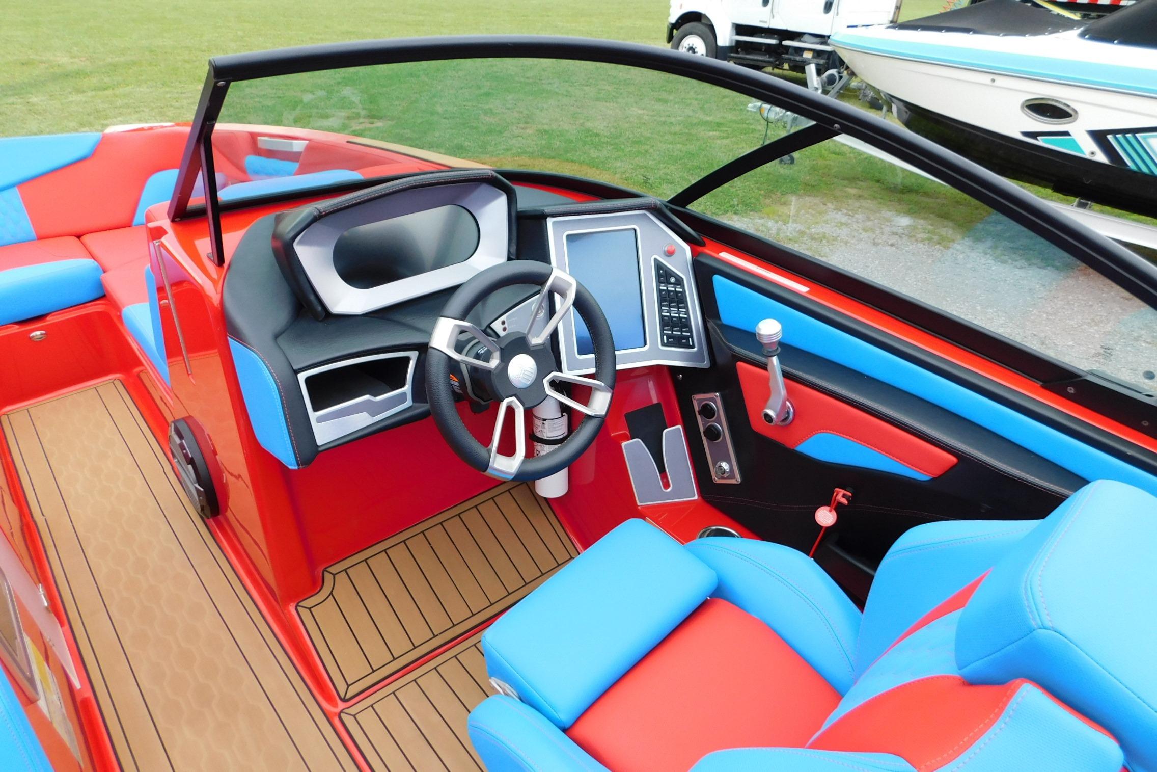 2022 MasterCraft NXT24 boat interior with vibrant red and blue seating, modern dashboard, and steering wheel.