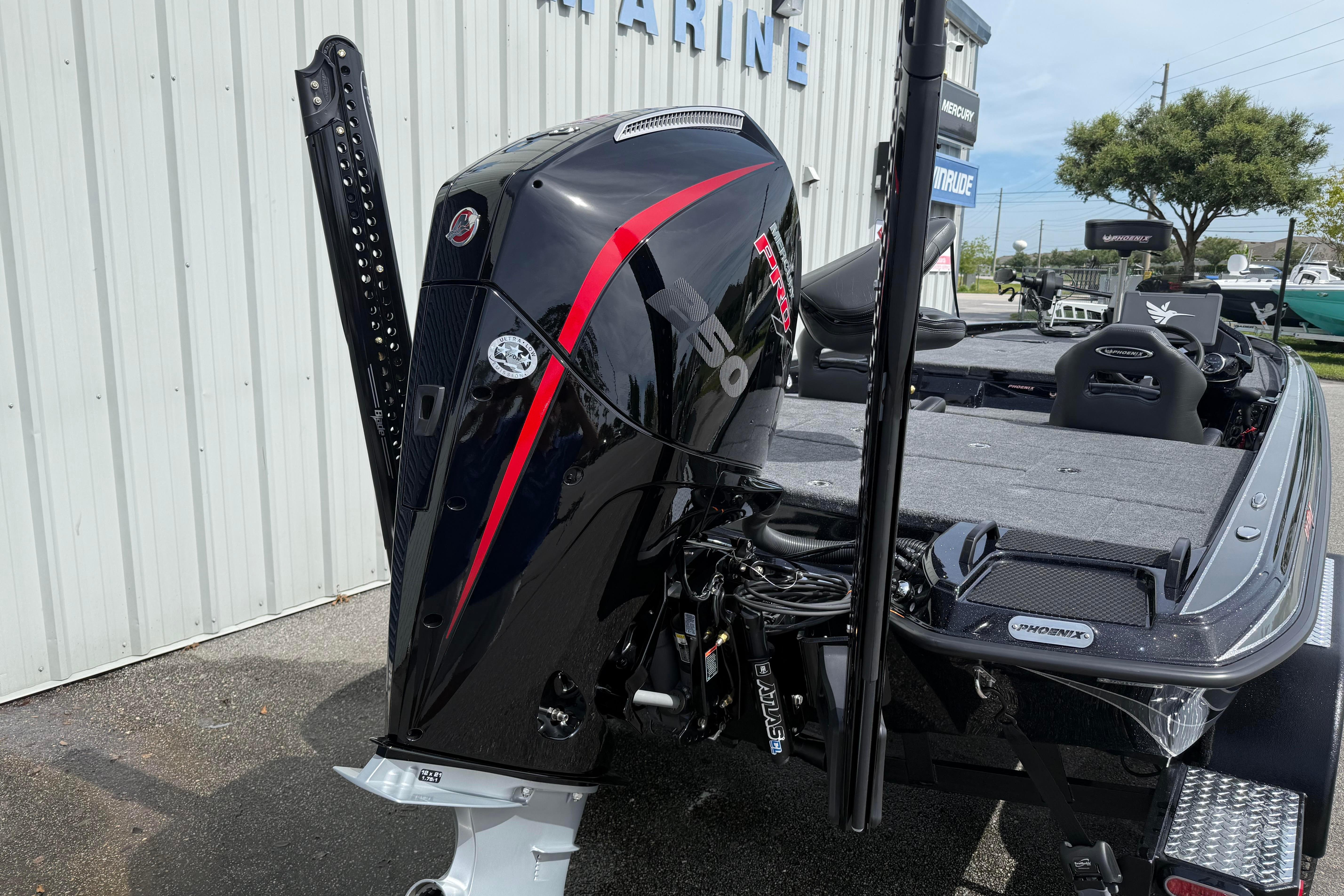 2027 Phoenix 921 Elite X boat with powerful outboard motor, parked near a marine facility.