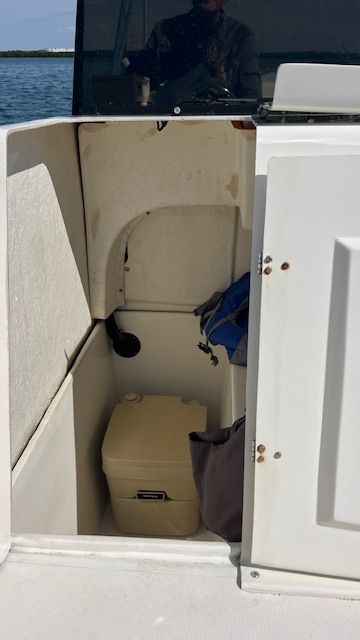 A storage compartment on a 2017 Beachcat Catamaran with a portable toilet and bags.