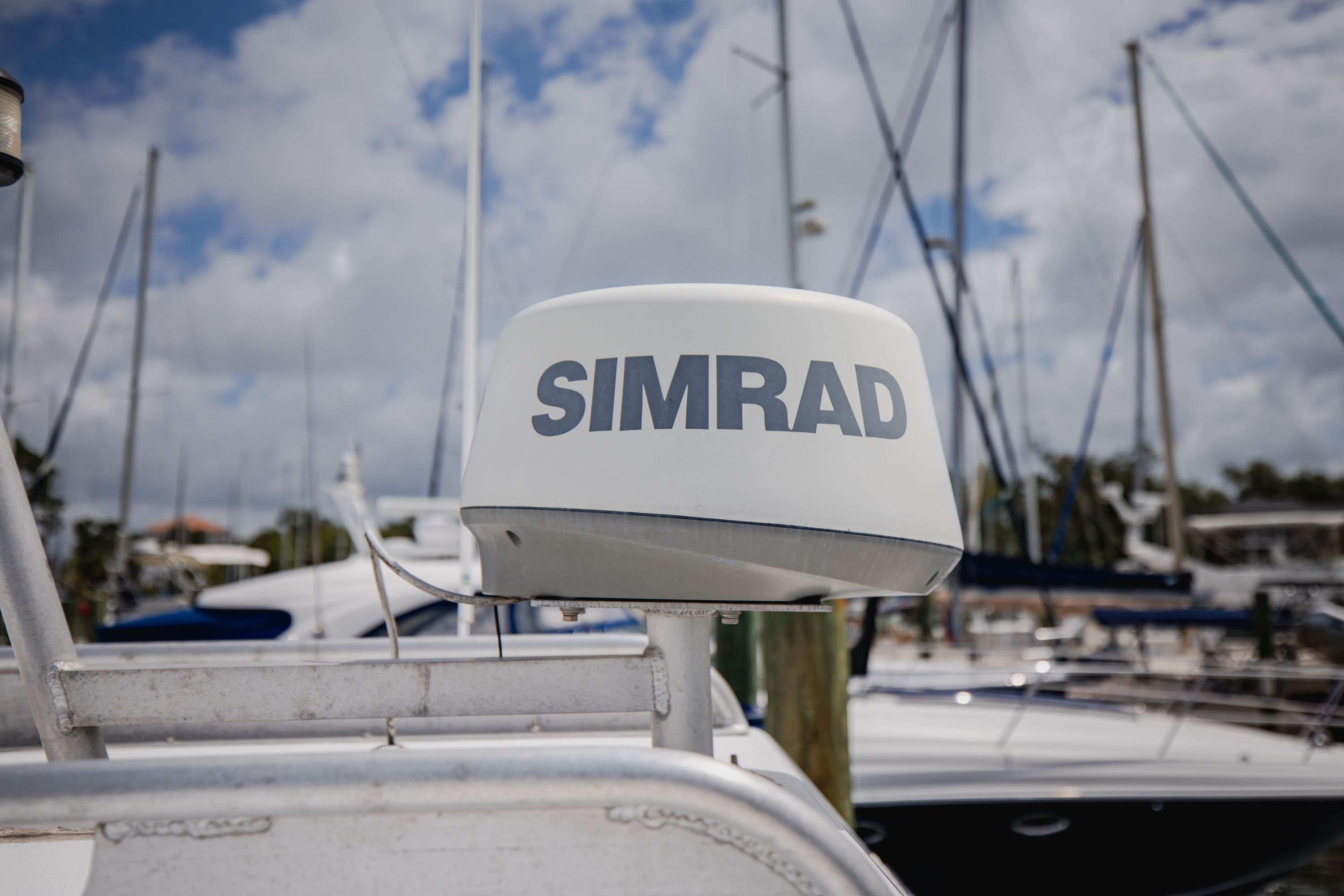 Simrad radar on a boat in a marina, surrounded by other boats and masts.