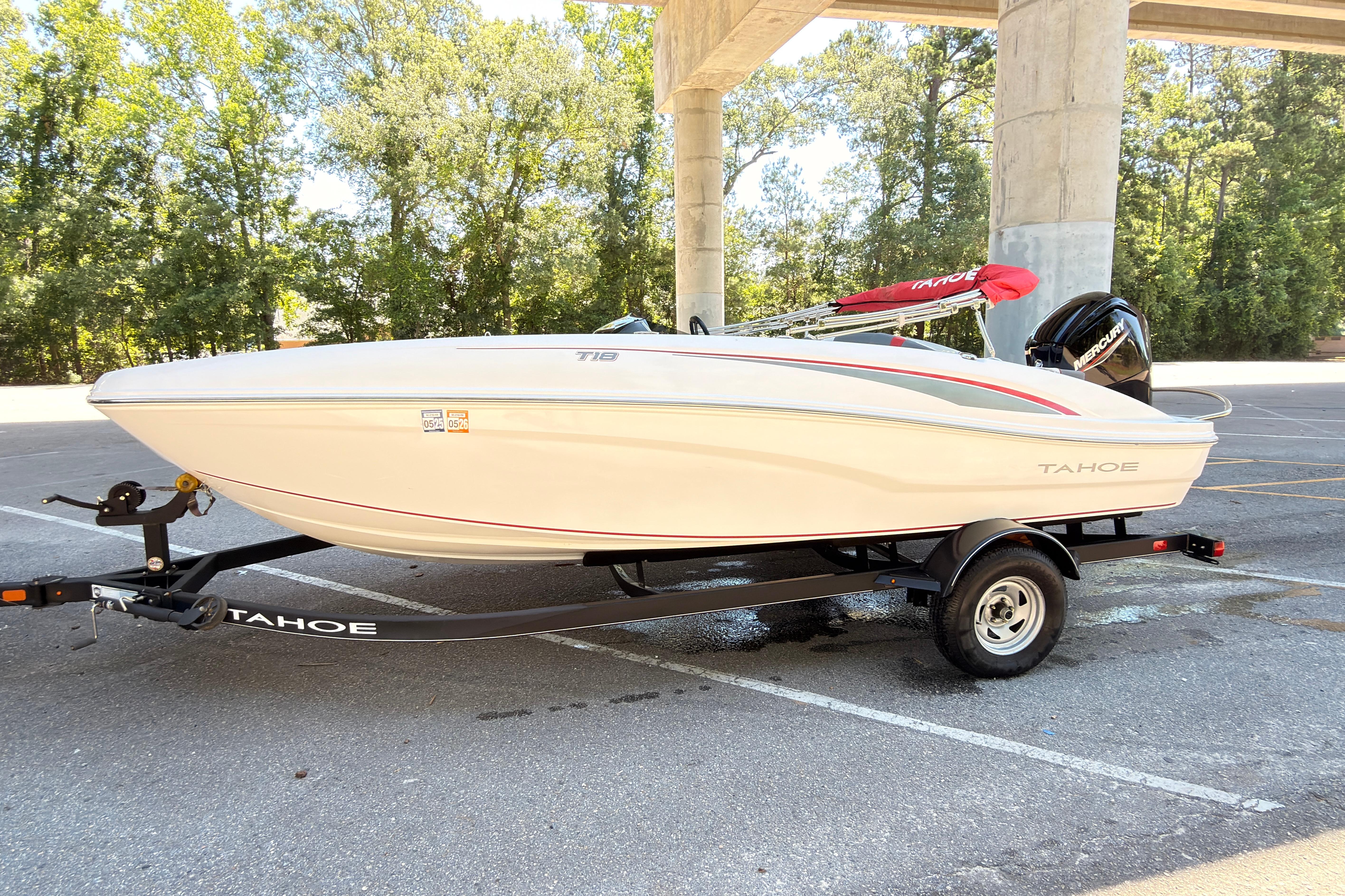 2022 Tahoe T18 boat on trailer in parking lot, surrounded by trees.