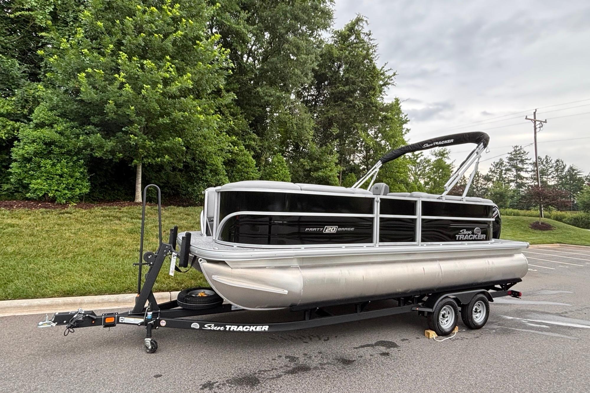 2026 Sun Tracker Party Barge 20 DLX pontoon boat on trailer, parked outdoors.