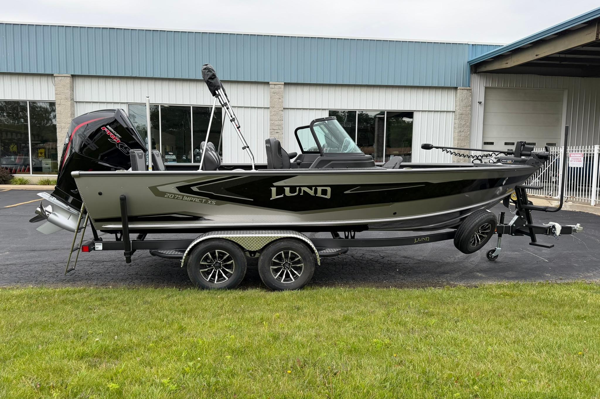 2027 Lund 2075 Impact XS boat on trailer, parked outside a building.