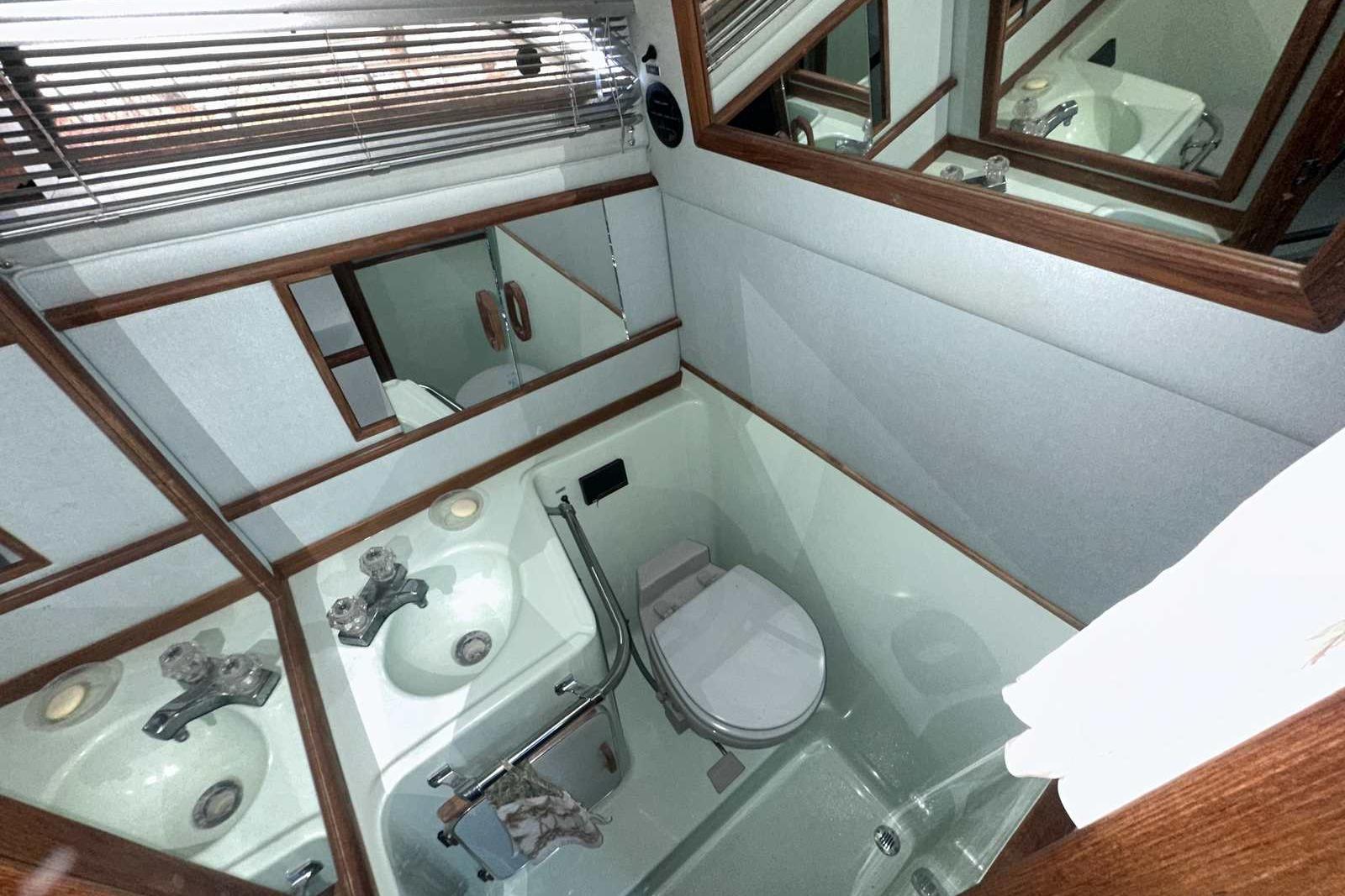 1987 Sea Ray 300 Sundancer bathroom with sink, toilet, and mirrors.