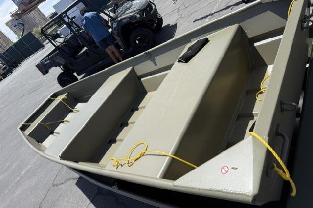 2026 Tracker Grizzly 12 Jon boat in a parking lot, with utility vehicle nearby.