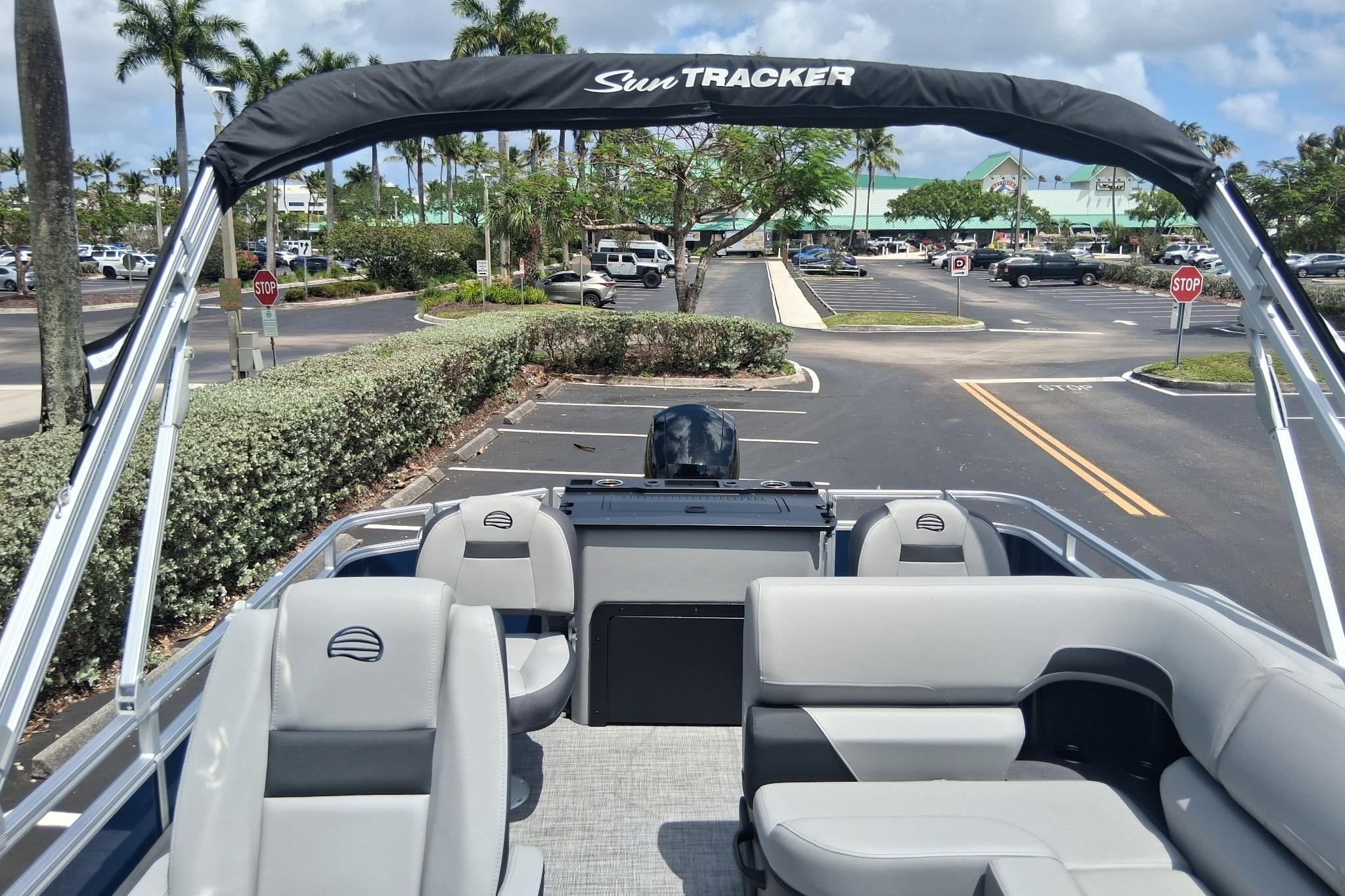 2026 Sun Tracker SportFish 22 DLX pontoon boat parked in a sunny lot with palm trees.