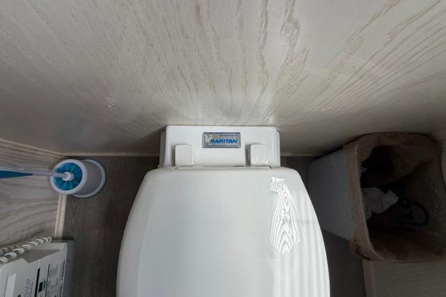 Toilet in 1997 Stardust Houseboat 18x83 bathroom with cleaning brush and waste bin.
