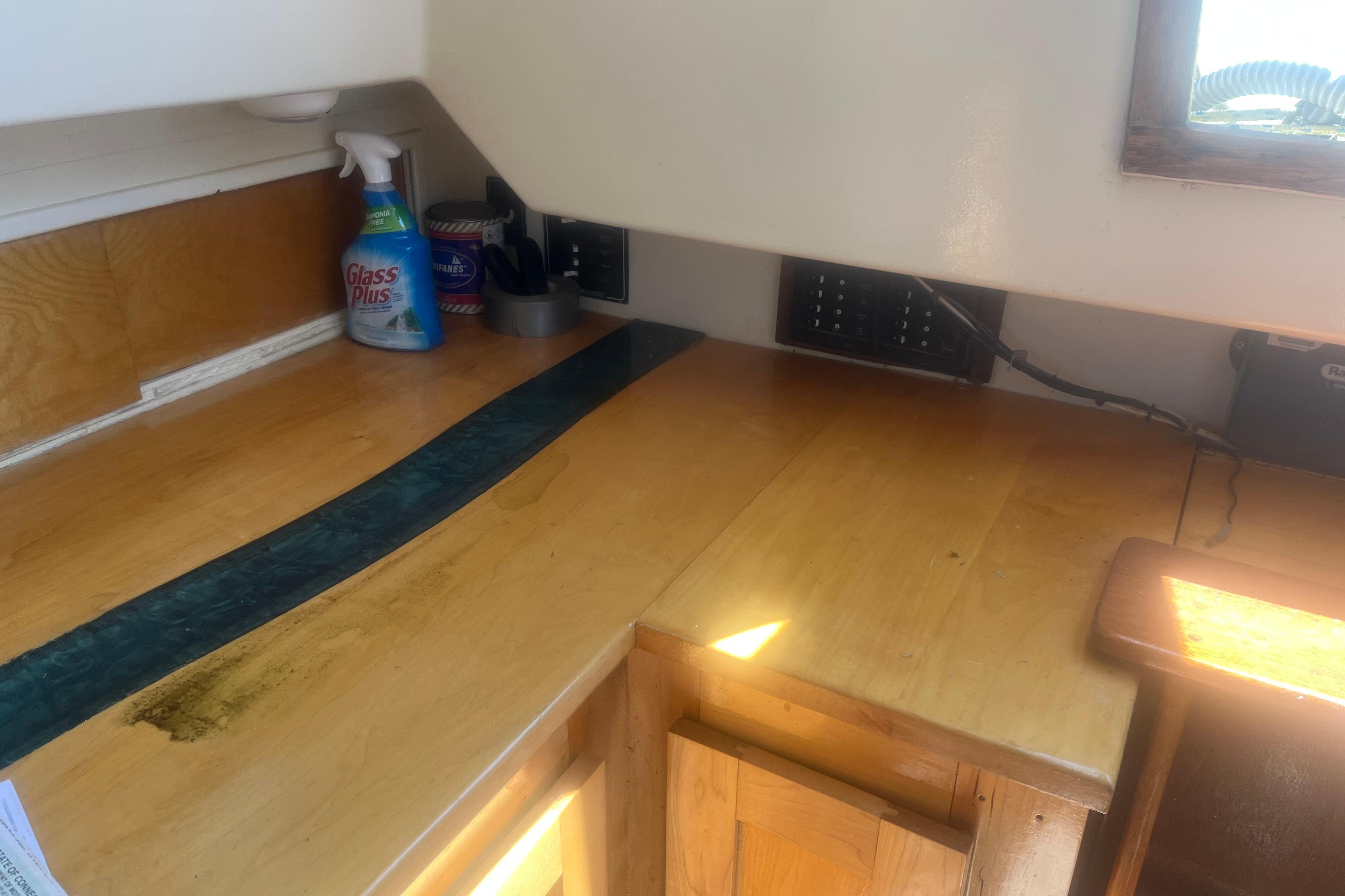 Interior of a 1972 C&C 30 sailboat with wooden cabinetry and cleaning supplies.
