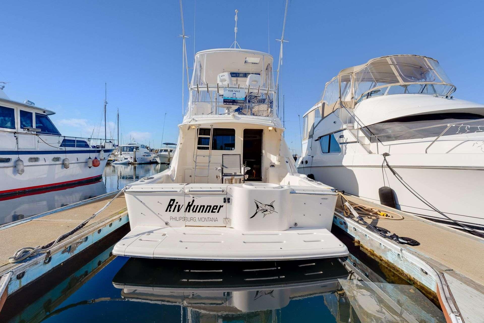 2004 Riviera Convertible yacht docked at marina, rear view with clear blue sky.