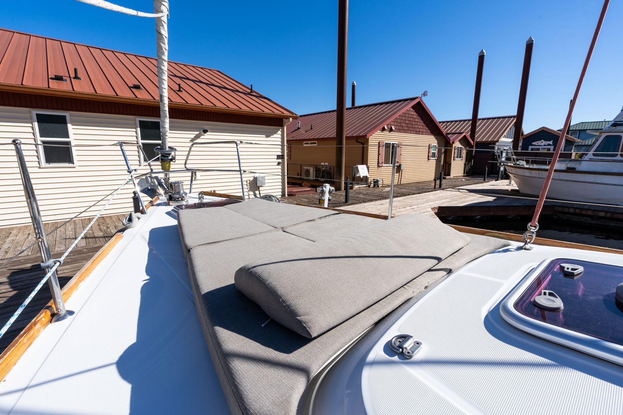 Beneteau Oceanis 50 sailboat deck with sunbathing area, docked near wooden buildings, 2013 model.