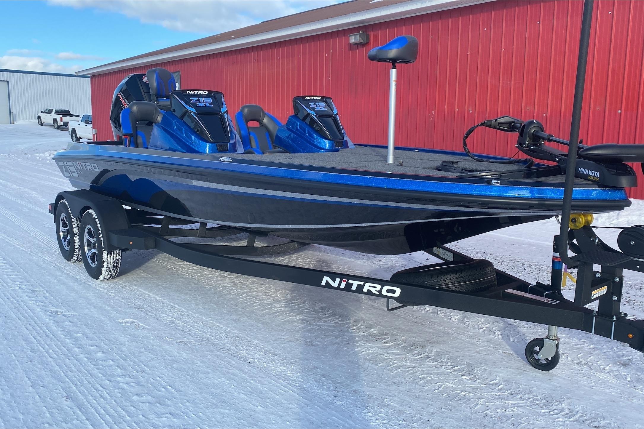 2026 Nitro Z19 XL boat on trailer, parked on snowy ground near red building.