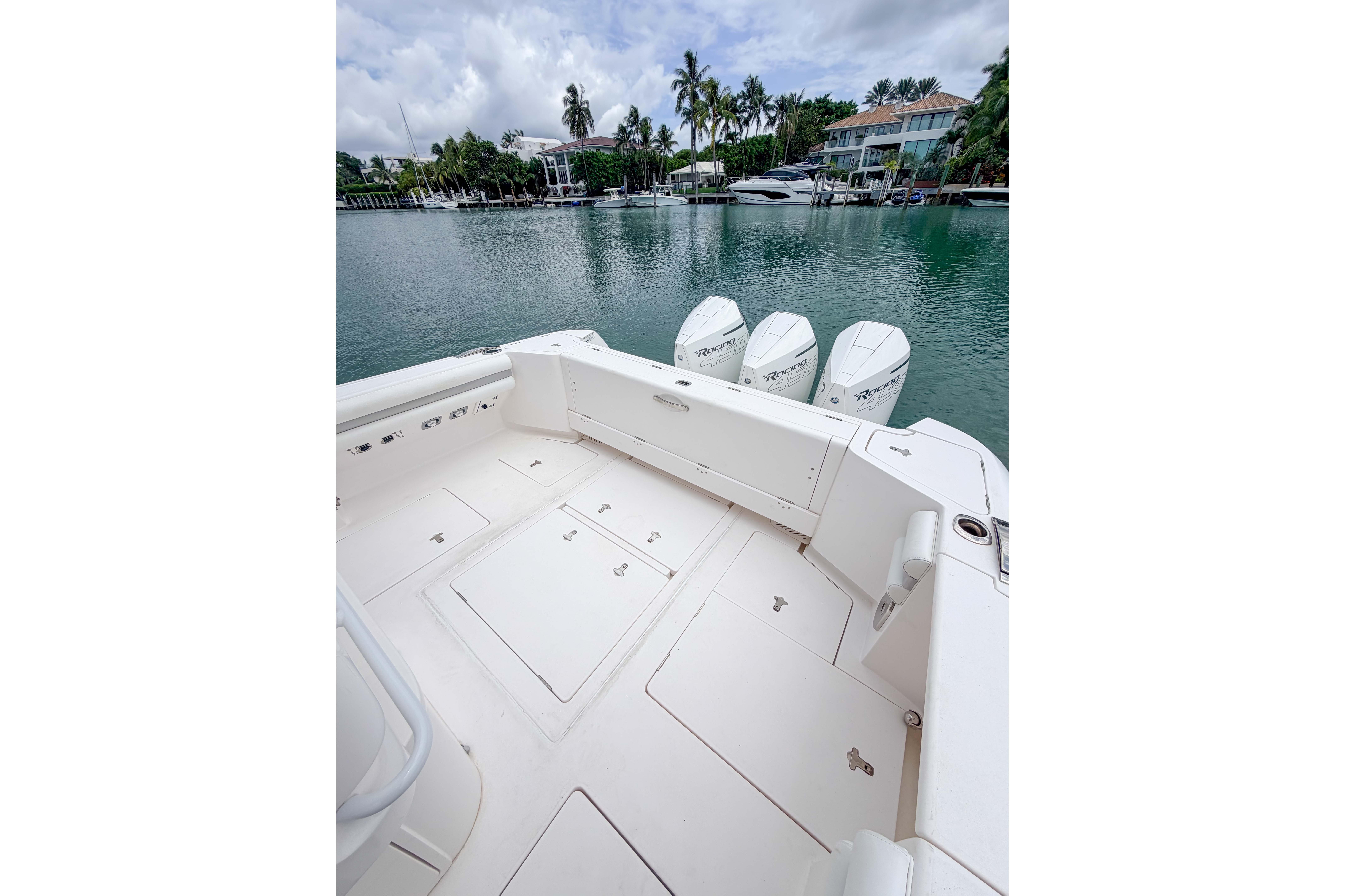 2021 Intrepid 409 Valor boat deck with quad engines, docked by waterfront homes.