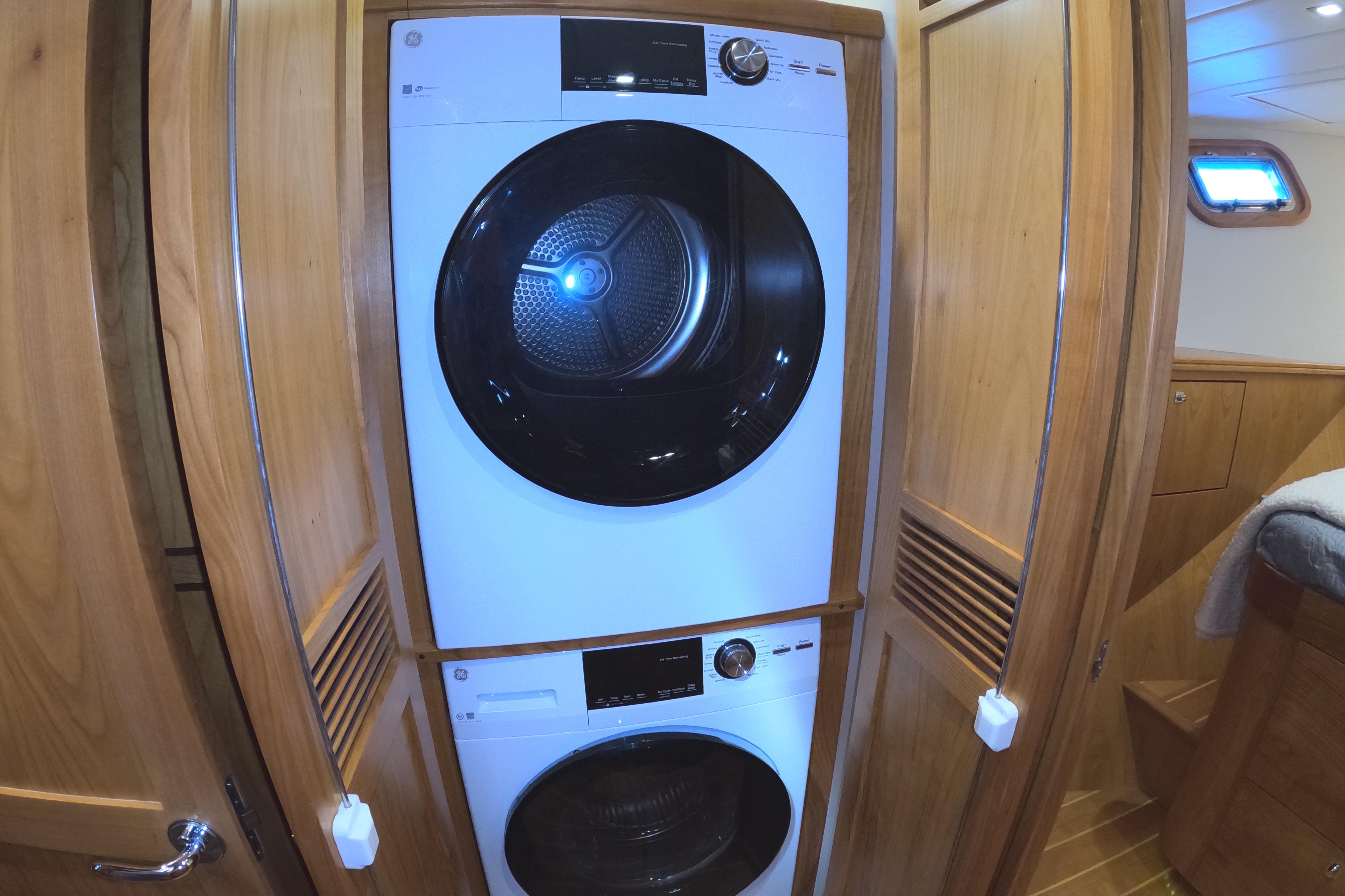 Stacked washer and dryer in 2021 Kadey-Krogen 50 Open yacht's wooden interior.