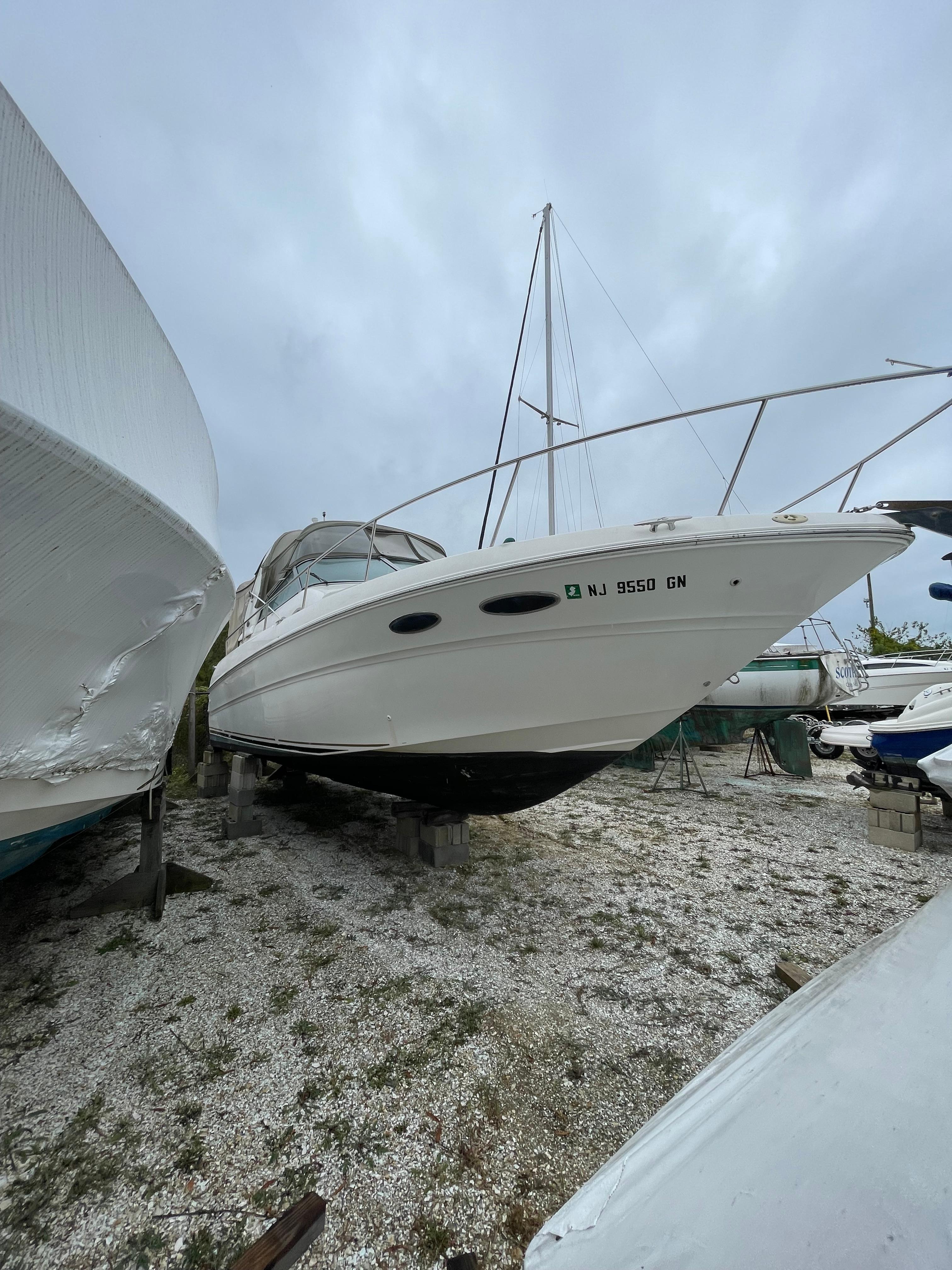 2001 Sea Ray 310 Sundancer boat on dry dock, overcast sky.
