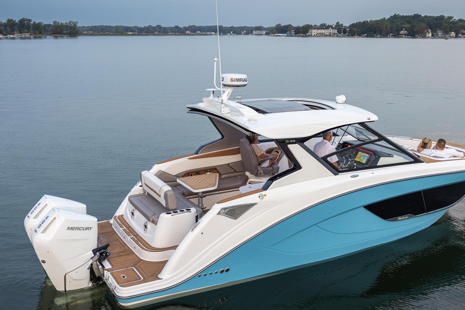 2026 Hurricane SunDeck 3200 OB boat on calm lake, featuring sleek design and powerful Mercury engines.