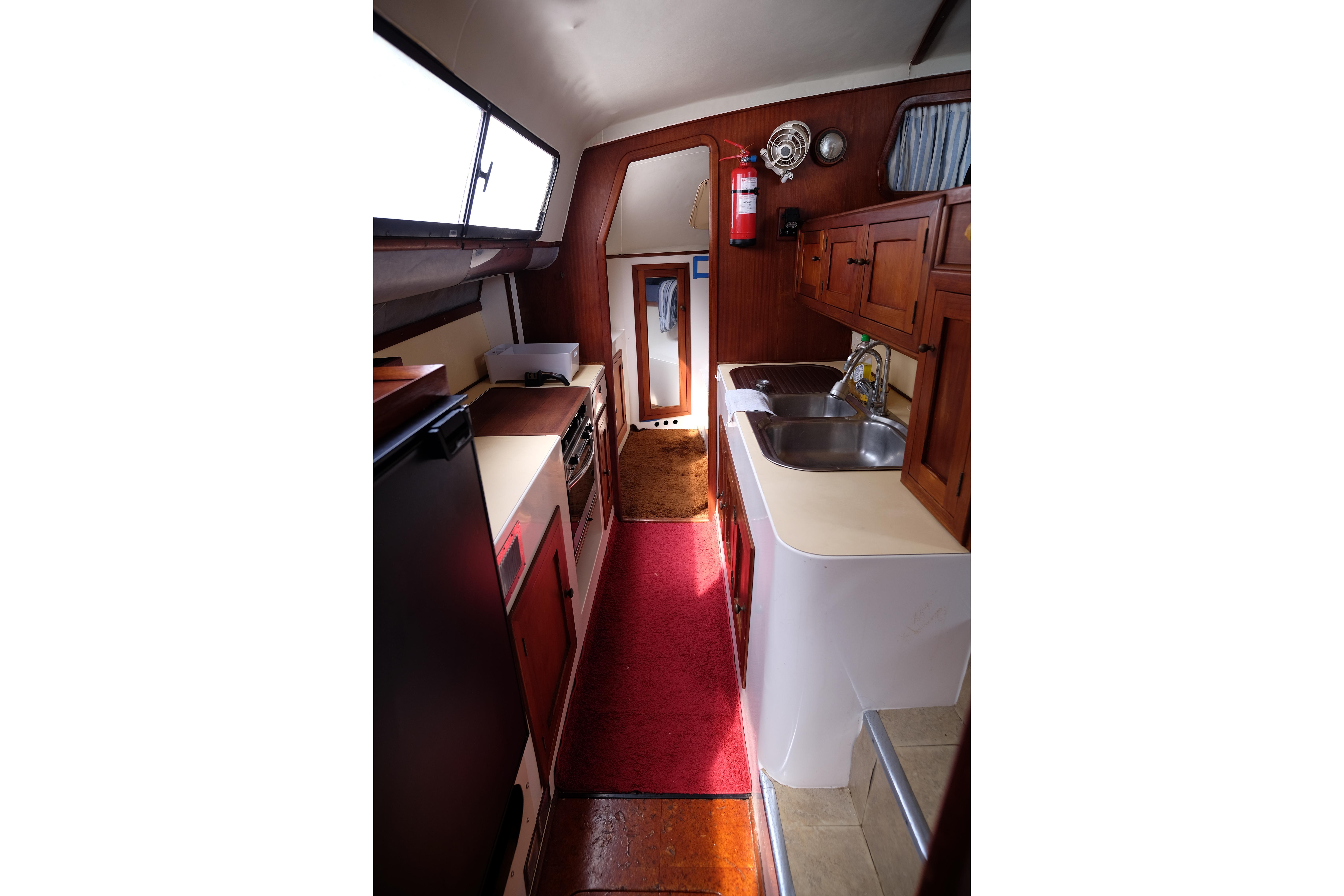 1996 Simpson Inspiration yacht interior with wooden cabinets, dual sinks, and red carpet.
