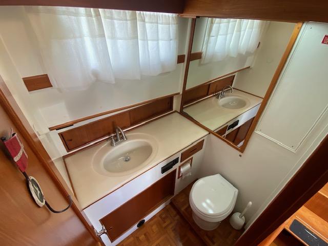 Bathroom interior of 1993 Grand Banks Classic yacht with sink, mirror, and toilet.