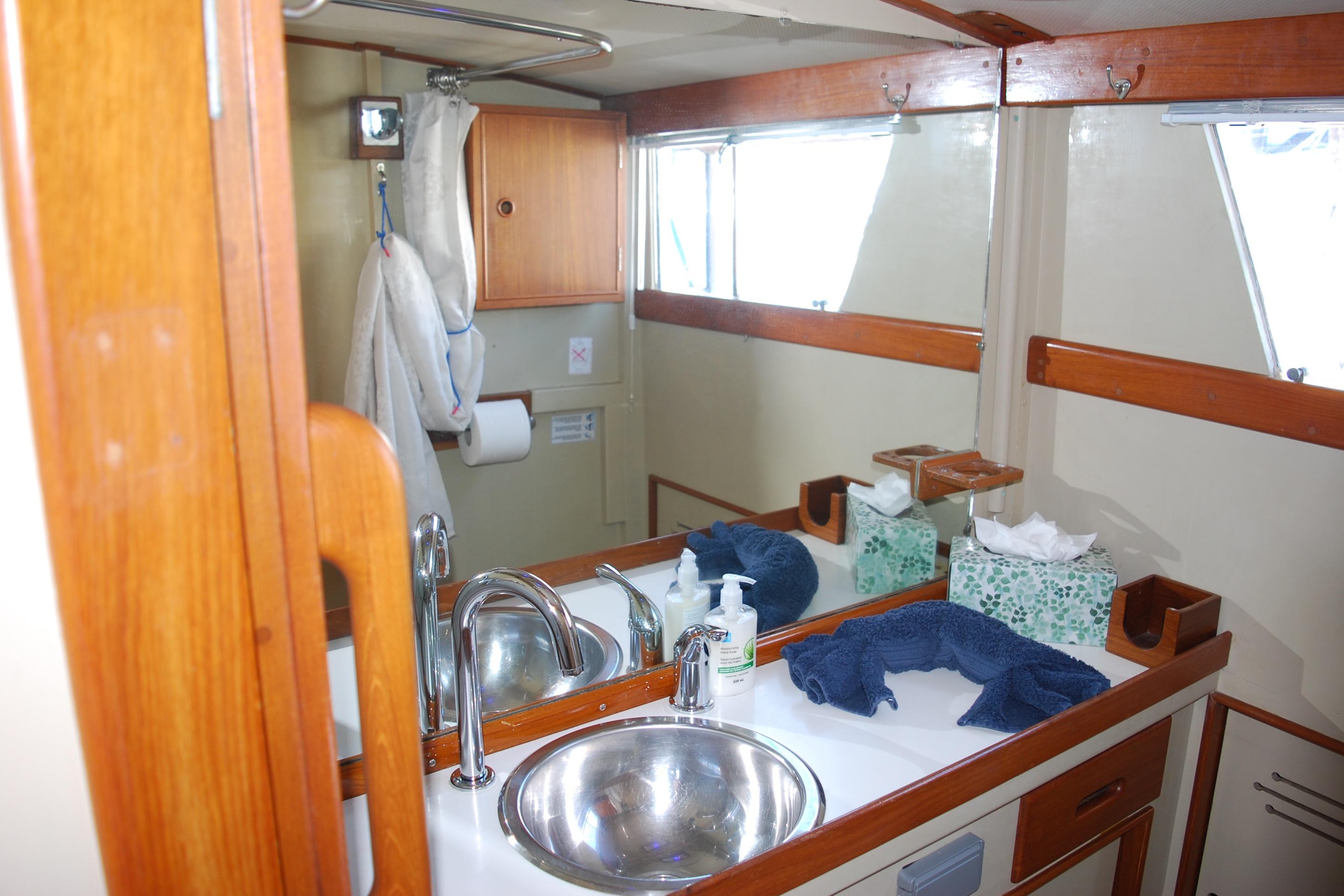 1971 Grand Banks 36 Classic yacht bathroom with sink, mirror, and wooden cabinetry.
