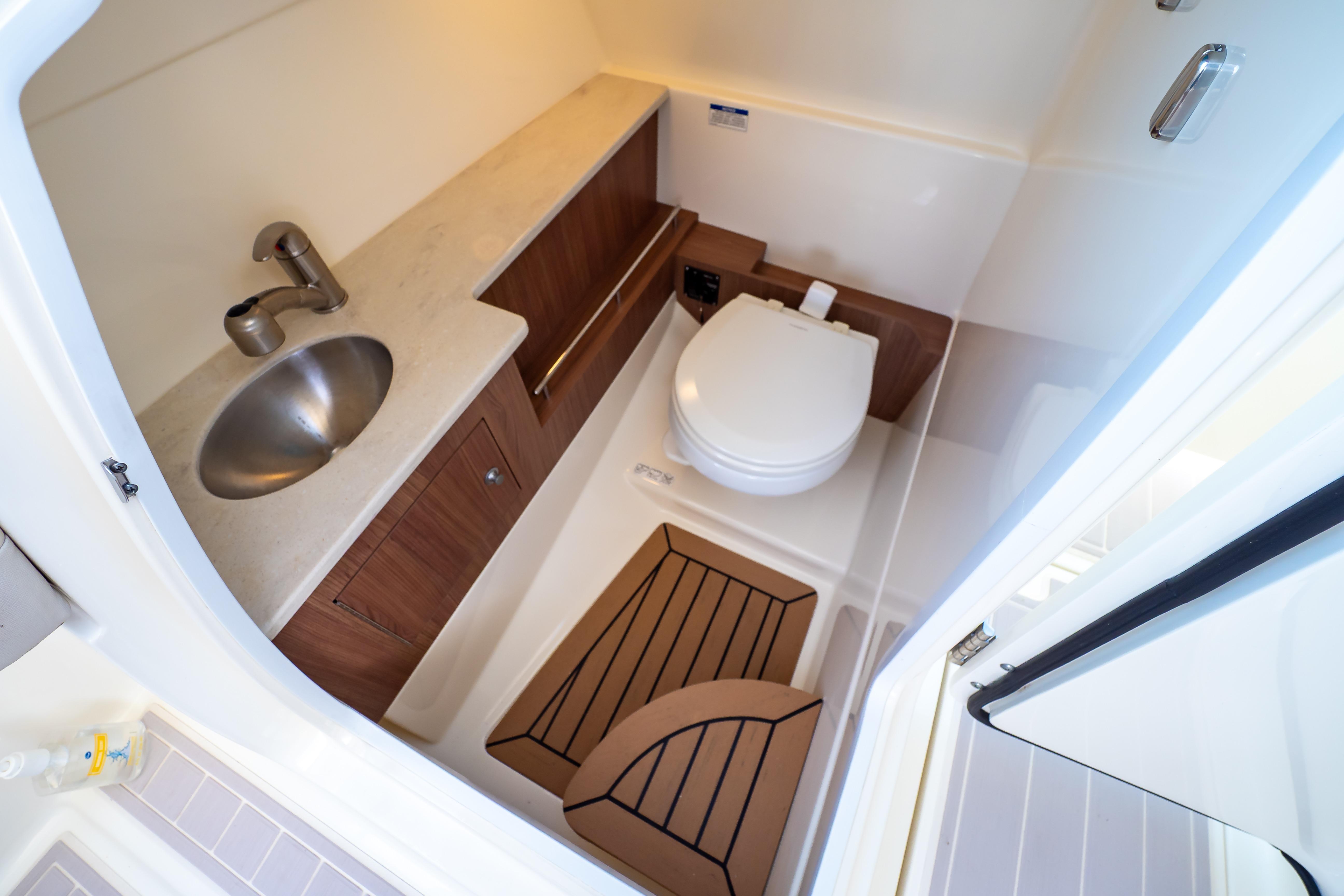 2019 Boston Whaler 270 Vantage boat bathroom with sink, toilet, and wooden flooring.